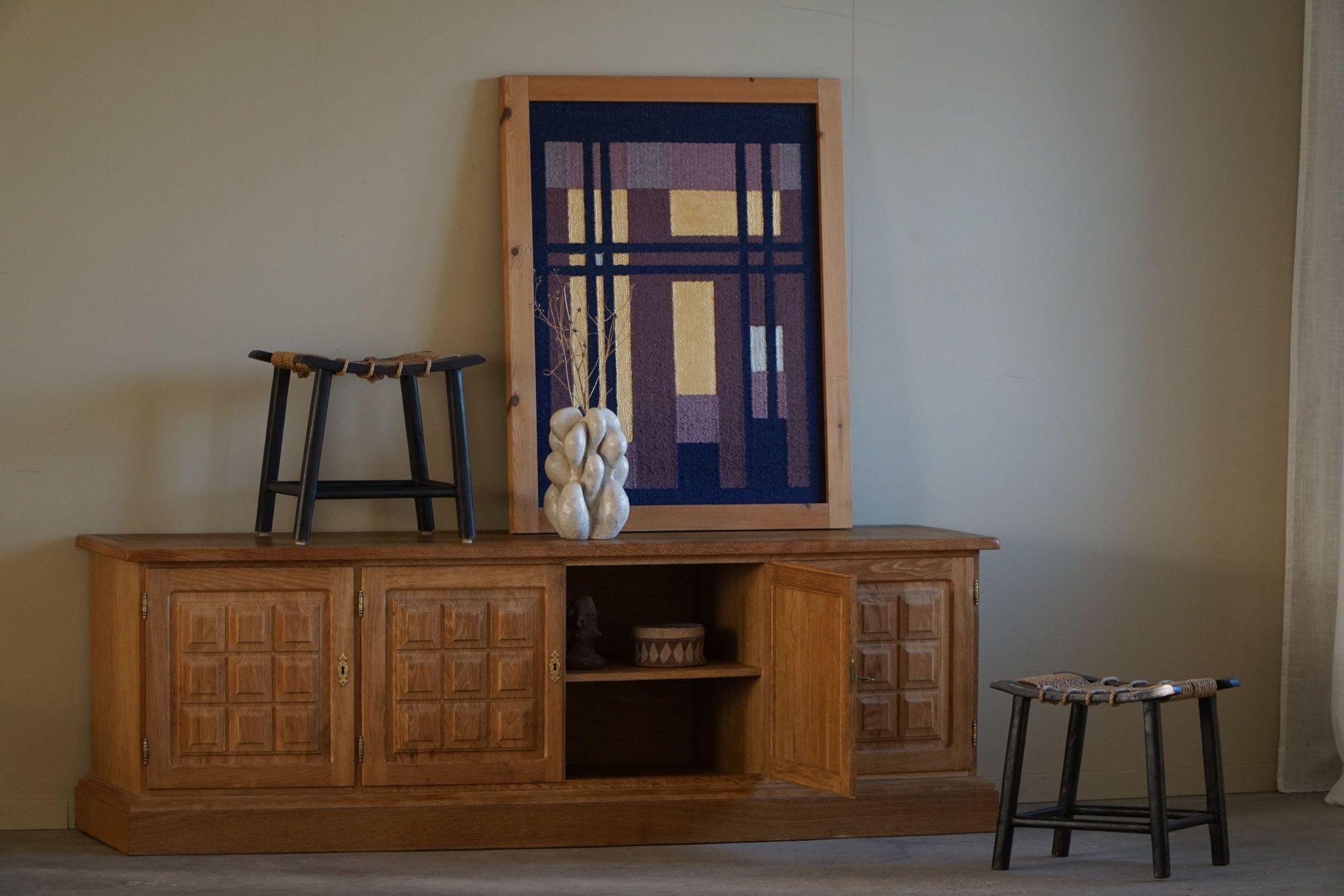 A spectacular low brutalist sideboard in oak and with brass fittings. Made by a Danish cabinetmaker in the 1950s. This piece is in a good vintage condition, with highlighted details such as the sculptural front design. 

This object will fit into