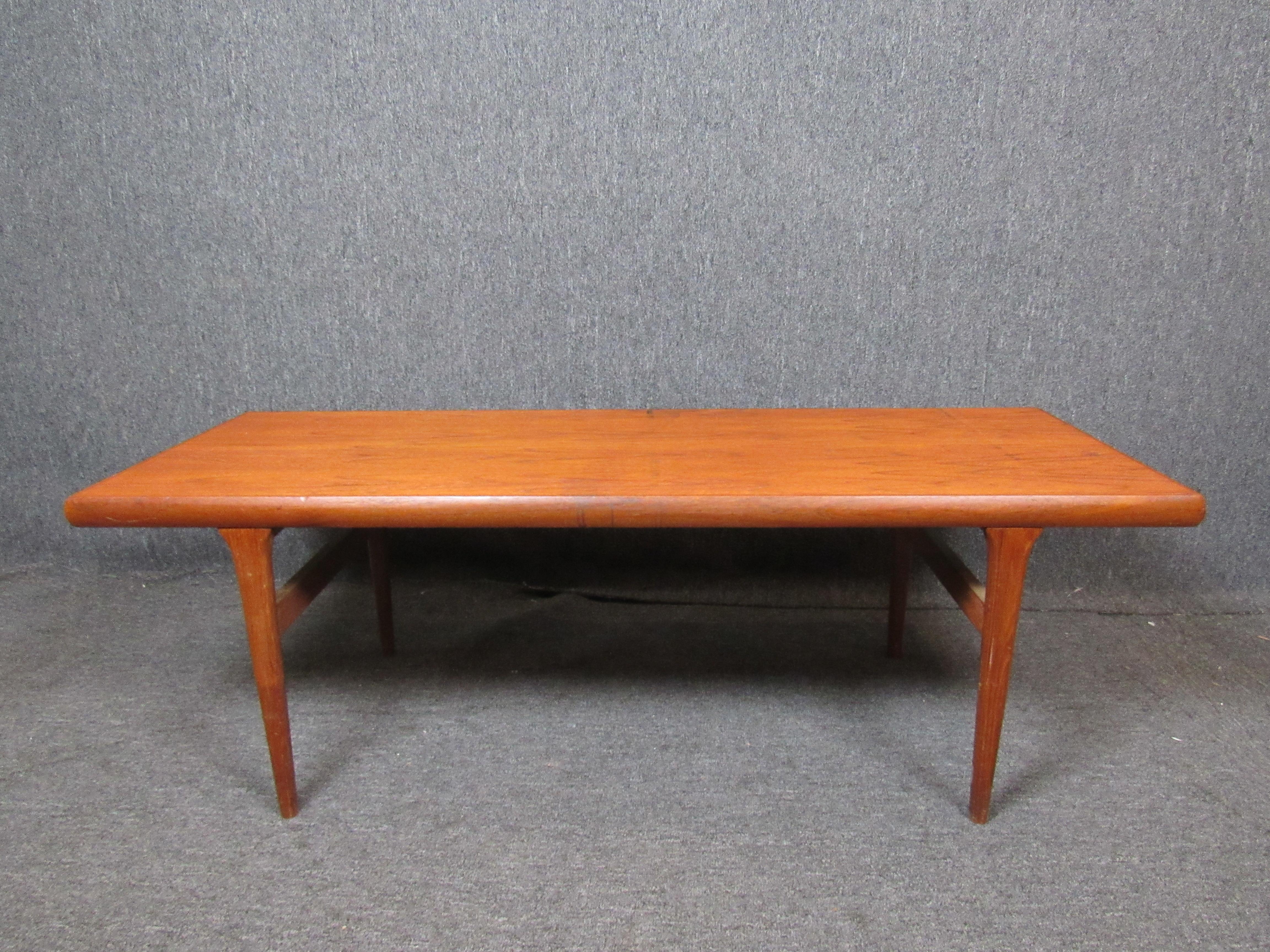 A classic mid-century Danish coffee table with a beautiful natural teak grain. Slender, carved legs give a sleek profile, sure to work well with a variety of styles. An ample tabletop makes this piece perfect for any room in the home, office, or