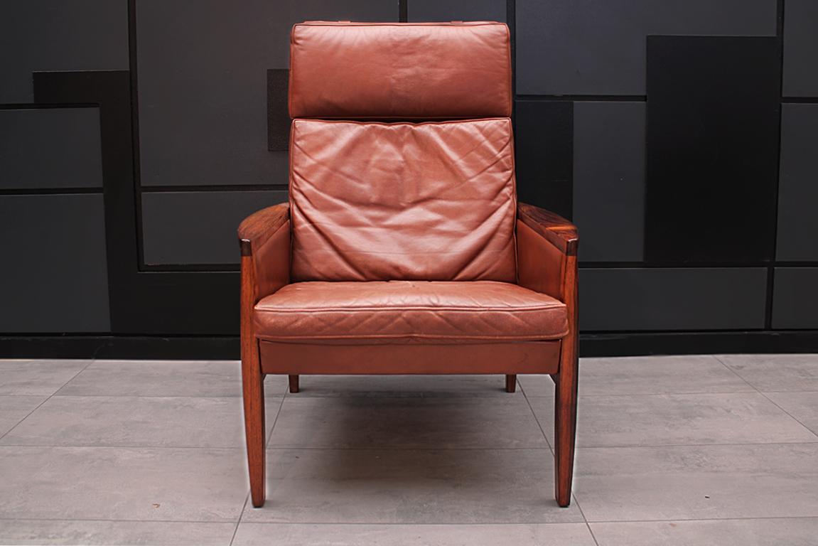 The model 2191 armchair was designed by Hans Olsen in 1961 and made in Denmark by Brdr. Juul Kristensen and features gently rounded wooden arms. In this chair we have the Classic combination of Rosewood and cognac leather that creates a warm and