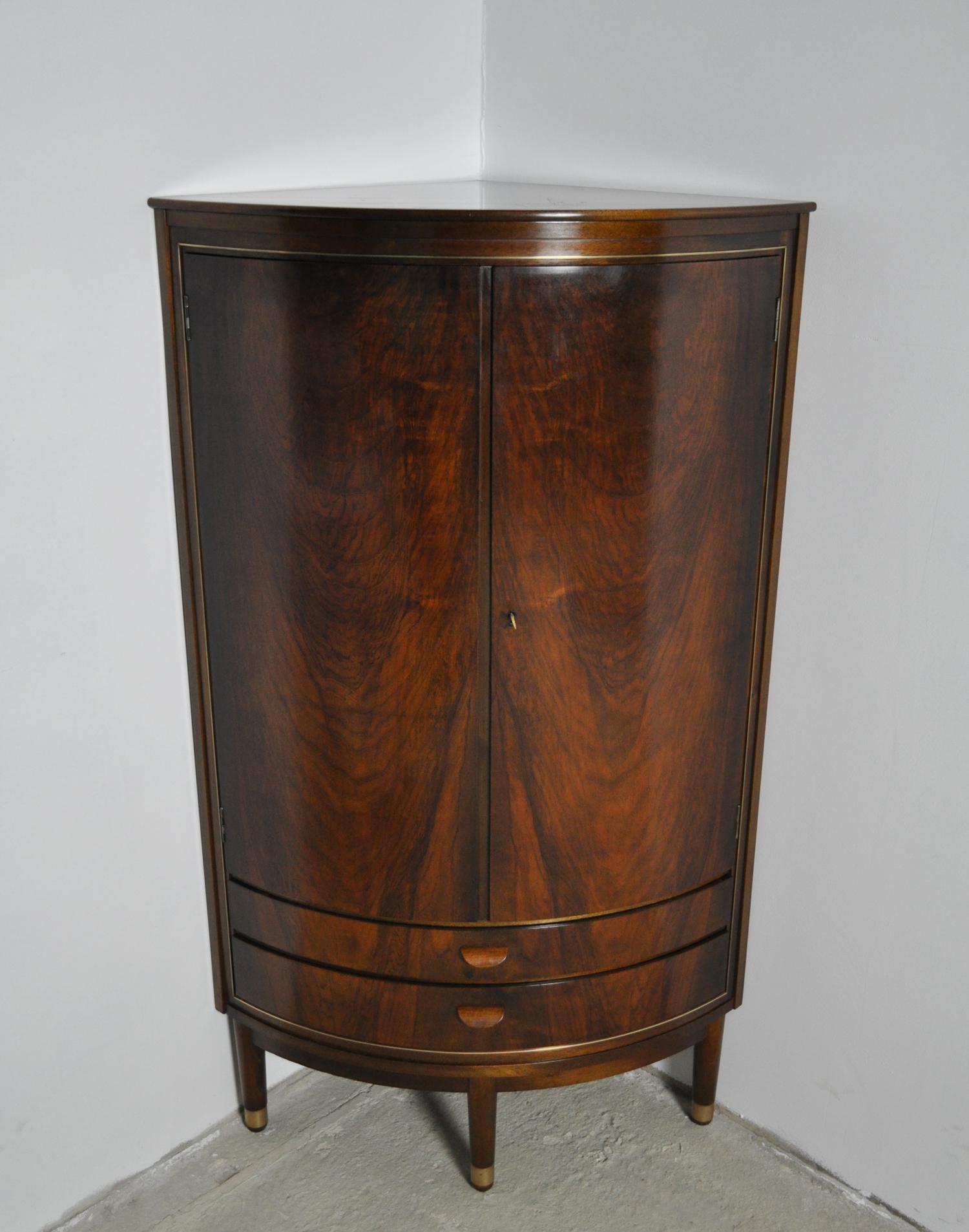 Corner Cupboard attributed to Agner Christoffersen. Made of veneered mahogany, front with two doors and 4 shelves behind. Underneath two drawers with beautifully curved handles. Brass inlays and feet.

Fine vintage condition, signs of wear