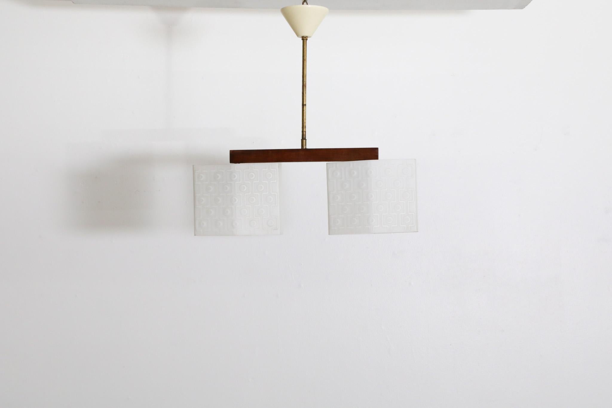 MId-Century double milk glass ceiling pendant with Brass stem on a teak bar and plastic canopy. Two tessellated milk glass shades textured with an embossed design that compliments the overall style and character of the light. In original condition