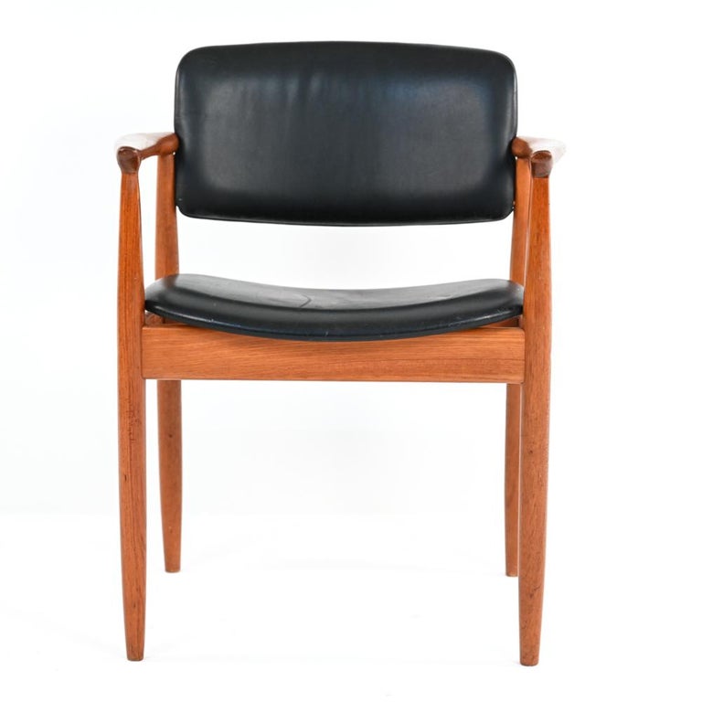 One need only look at the warm, rubbed patina of the armrests to know that this chair is as comfortable as it is stylish. With its solid teak frame, gracefully sculpted arms and simple black leather upholstery, this piece adds an element of subtle