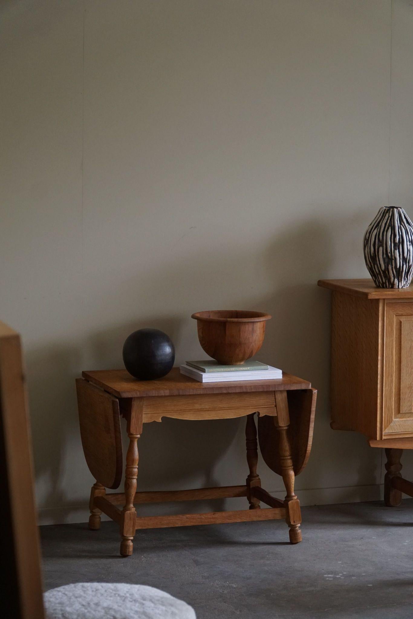 Presenting a neat folding side table in oak, made in the style of Henning Kjærnulf from the vibrant 1960s era. Crafted with precision and finesse, this table embodies the essence of Scandinavian design simplicity. Constructed from oak, this table