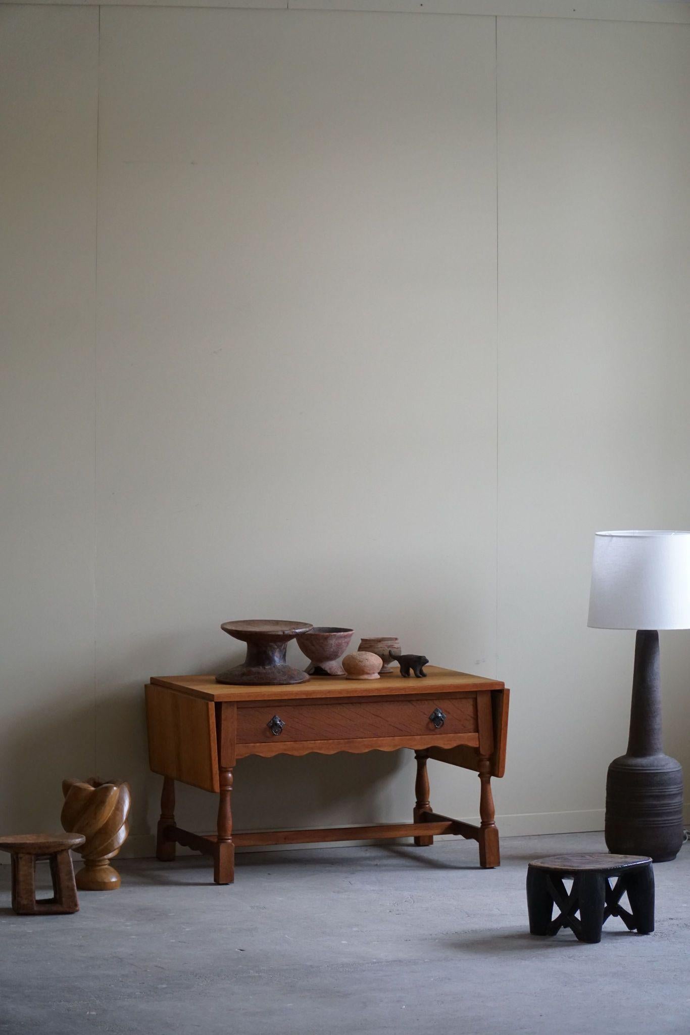 Wir stellen einen dänischen Klapptisch aus der Mitte des Jahrhunderts vor, der aus Eichenholz gefertigt und vom ikonischen Stil von Henning Kjærnulf aus den 1960er Jahren inspiriert ist. Der aus Eichenholz gefertigte Tisch strahlt Wärme und