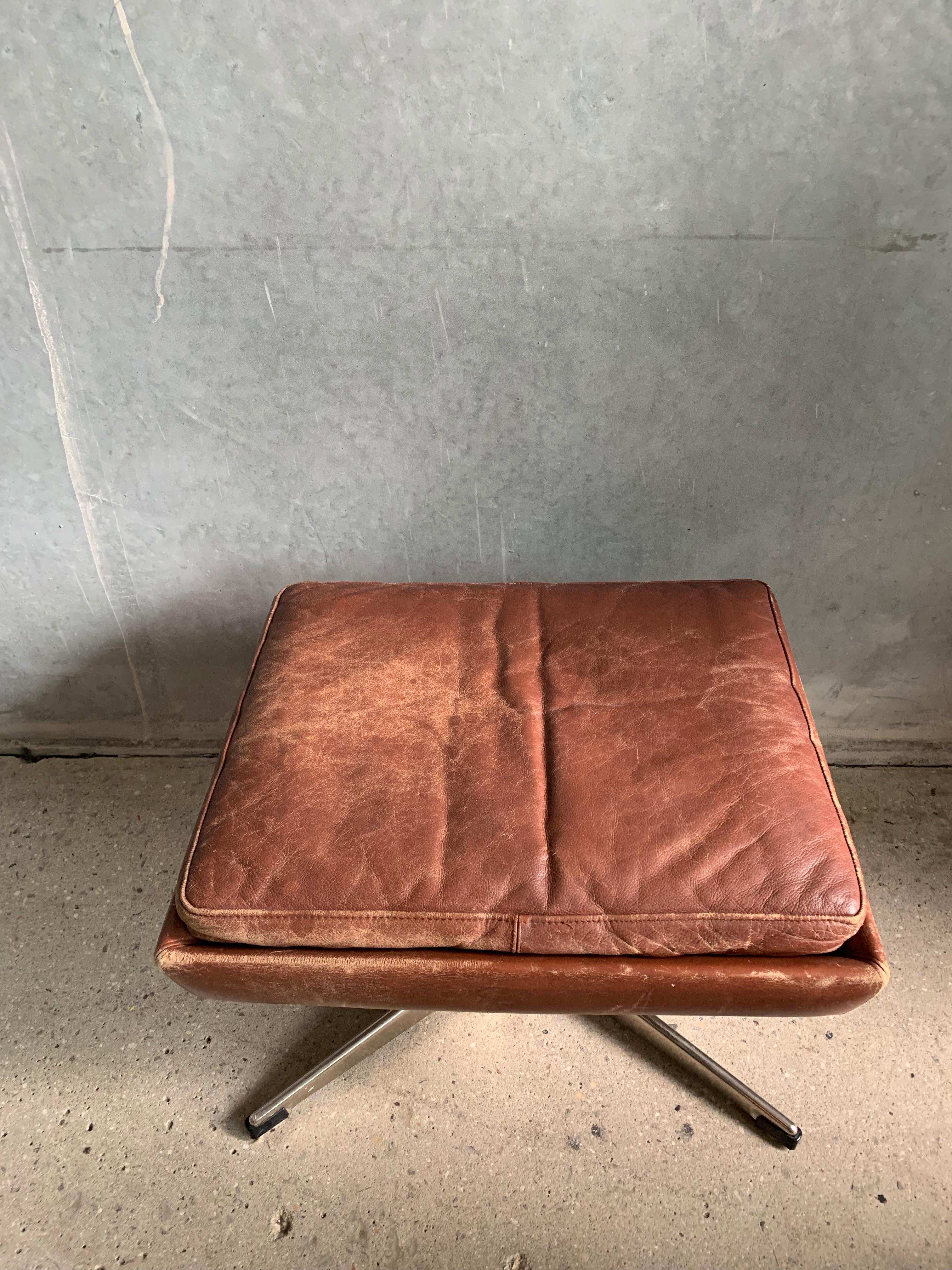 Beautiful brown leather footstool with lovely patina. Made in Denmark. Featuring a swivel chrome starbase.