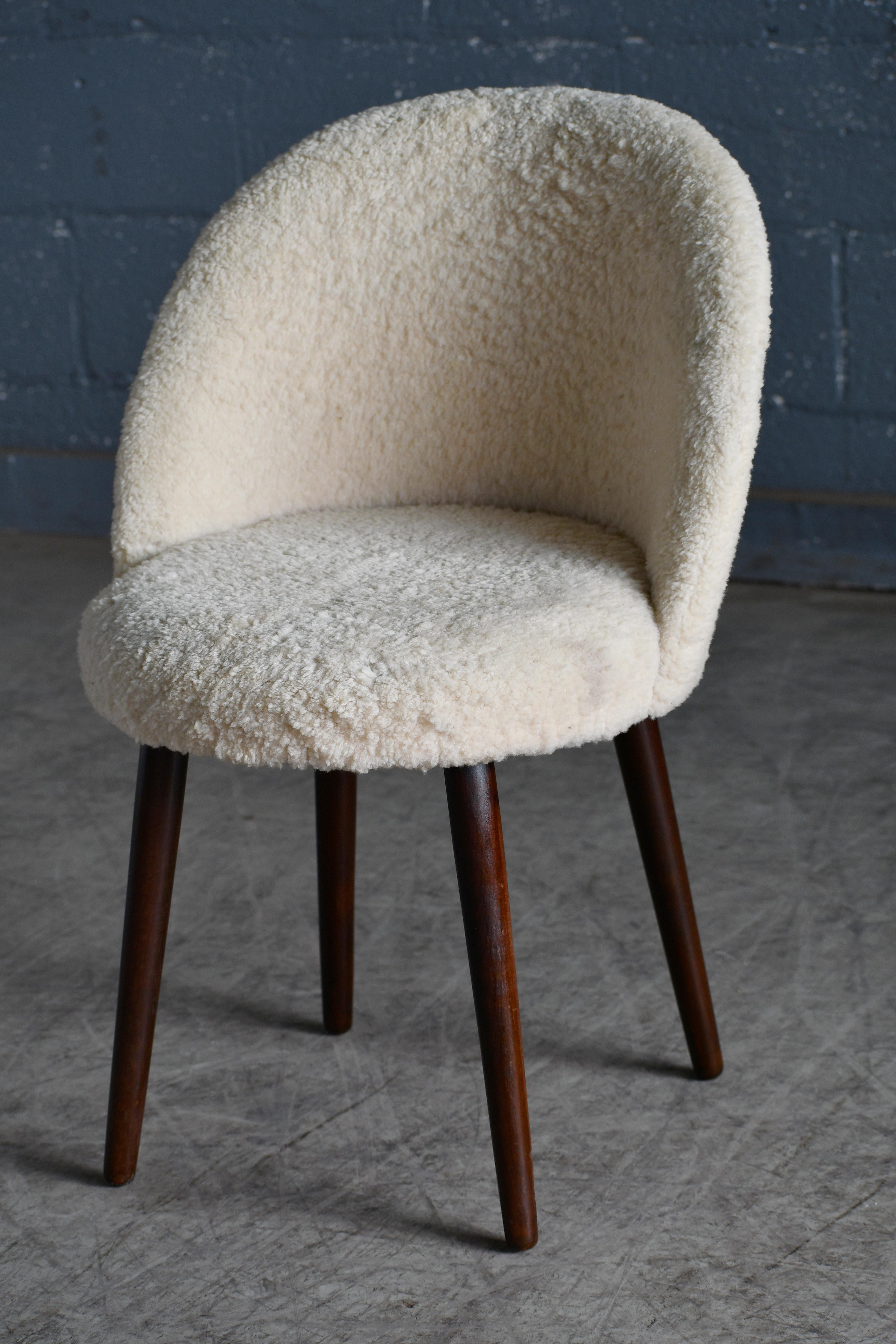 This is a great small vanity chair in the style of Frode Holm covered in plush lambskin. For the person that already has everything, this may be the one thing to get. The chair is comfortable and supportive with a curved backrest. Light but sturdy.