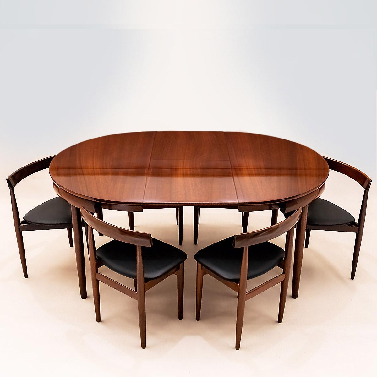 Danish Mid Century Hans Olsen Roundette space saving extending teak dining table with 6 black leather and teak chairs by Frem Røjle.

Originally designed by Hans Olsen in 1952 for Frem Røjle this dining set has since become an icon of classic