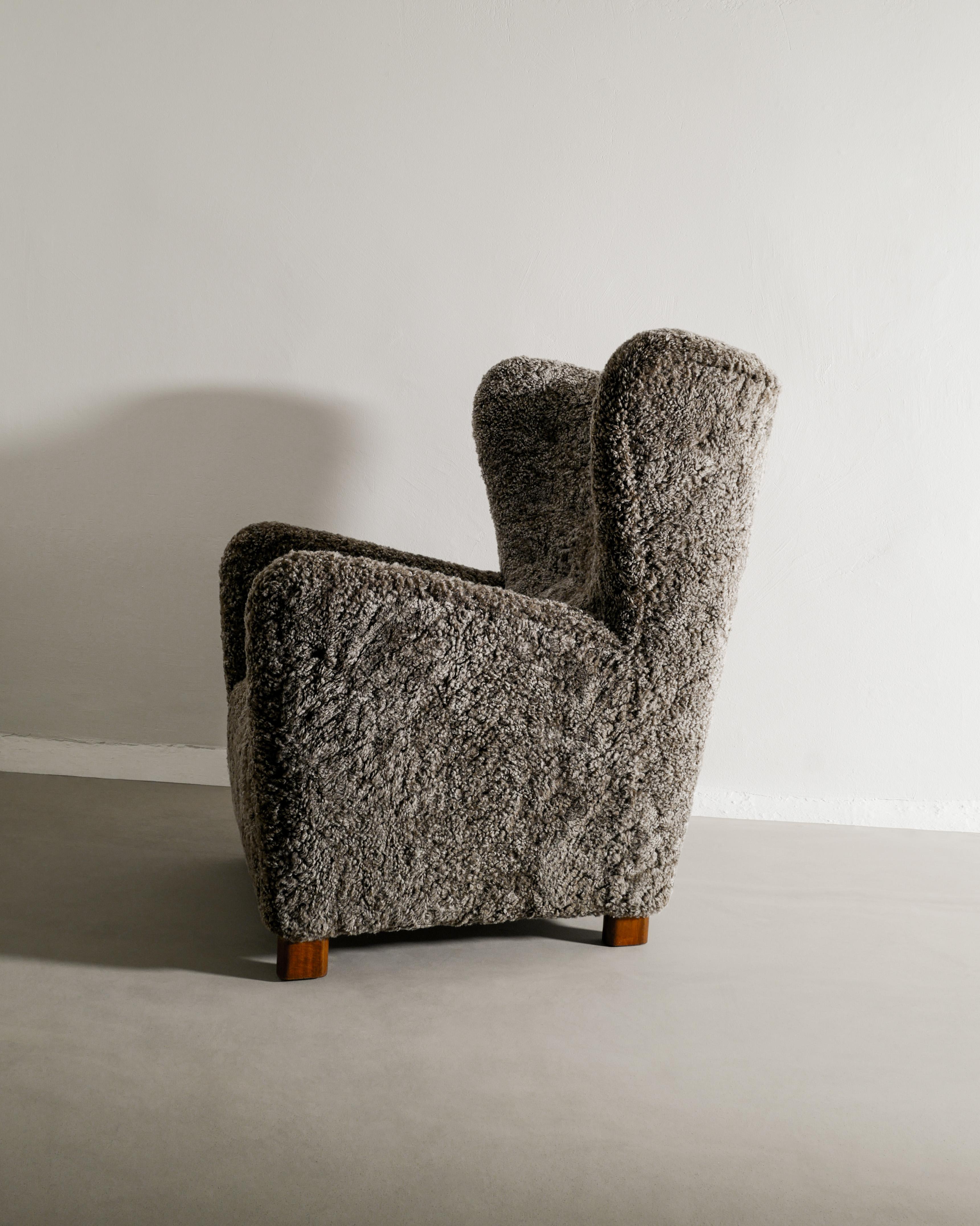 Rare Danish mid century high wingback armchair produced by Thorald Madsen Snedkeri Denmark, 1940s. In great condition and professionally restored and upholstered in dark grey colored sheepskin. 

Dimensions: H: 98 cm / 38.6