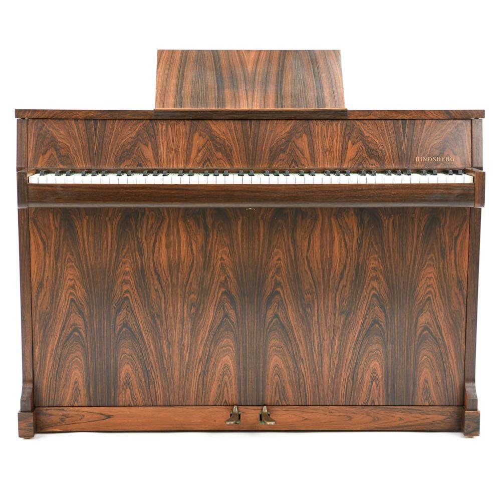 This gorgeous Danish midcentury pianette was produced by Hindsberg, circa mid-1960s. This pianette features stunning book-matched rosewood veneer that shows off the highly sought color and grain of rosewood. An integrated music stand collapses into