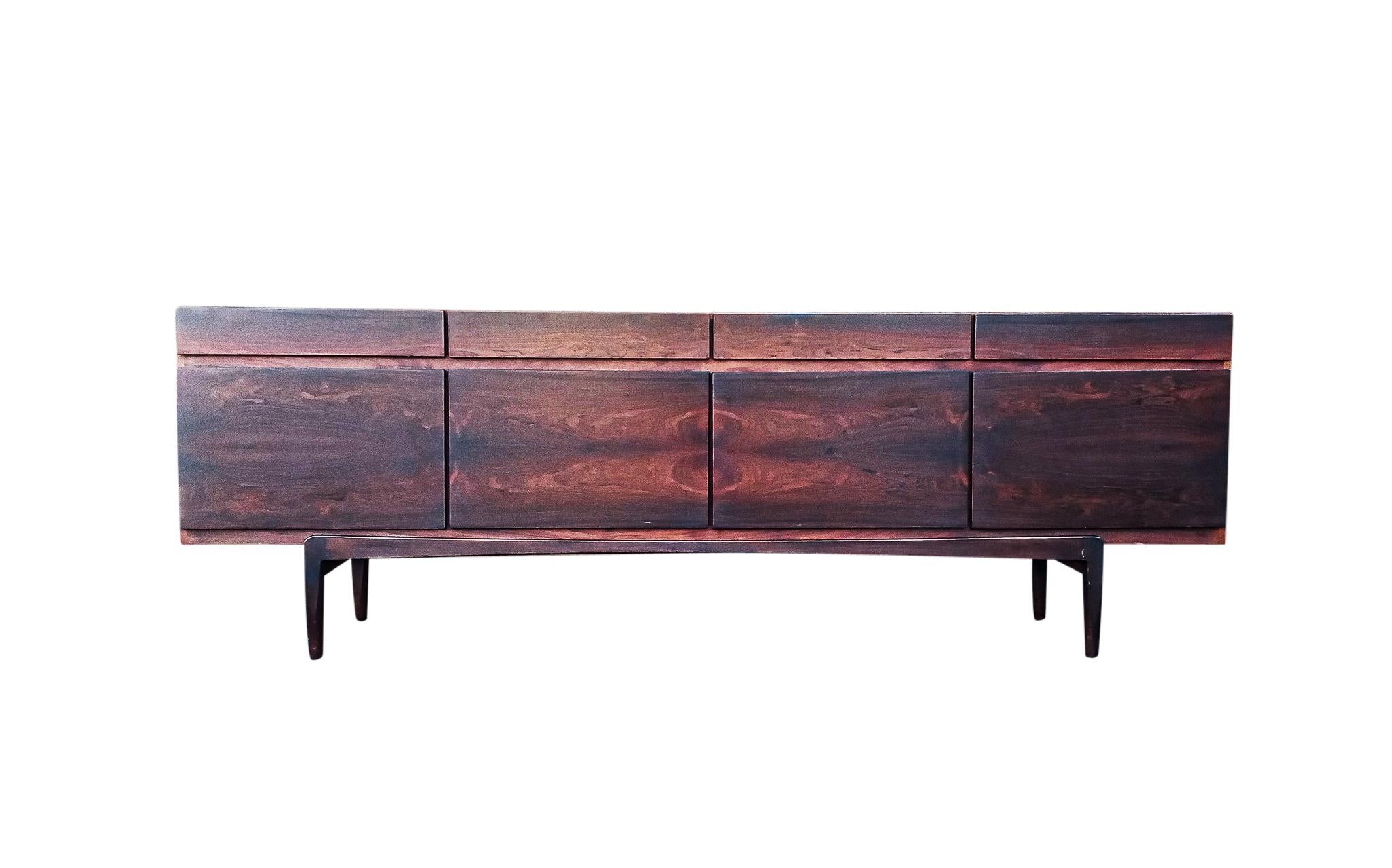 Fabulous and dramatic formal-scale bookmatched rosewood cabinet by legendary Danish designer Ib Kofod-Larsen. Ours features four drawers above four doors concealing five sliding shelves and one rosewood removable shelf and another two in glass, not