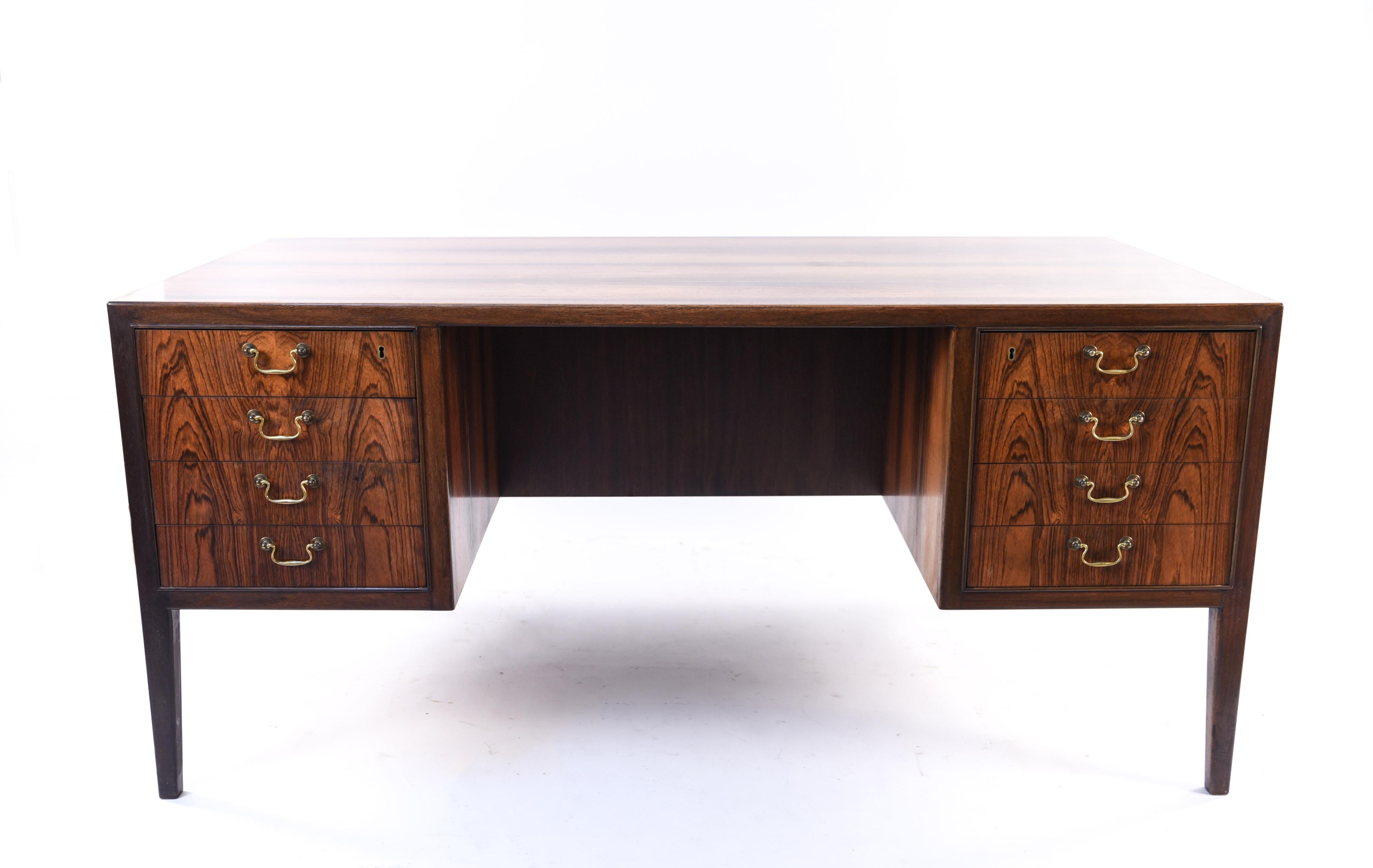 This Danish midcentury rosewood desk by Jacob Kjaer has a beautiful rosewood surface for a rich appearance. With brass bale handles, this piece brings a traditional touch to an otherwise modern piece.