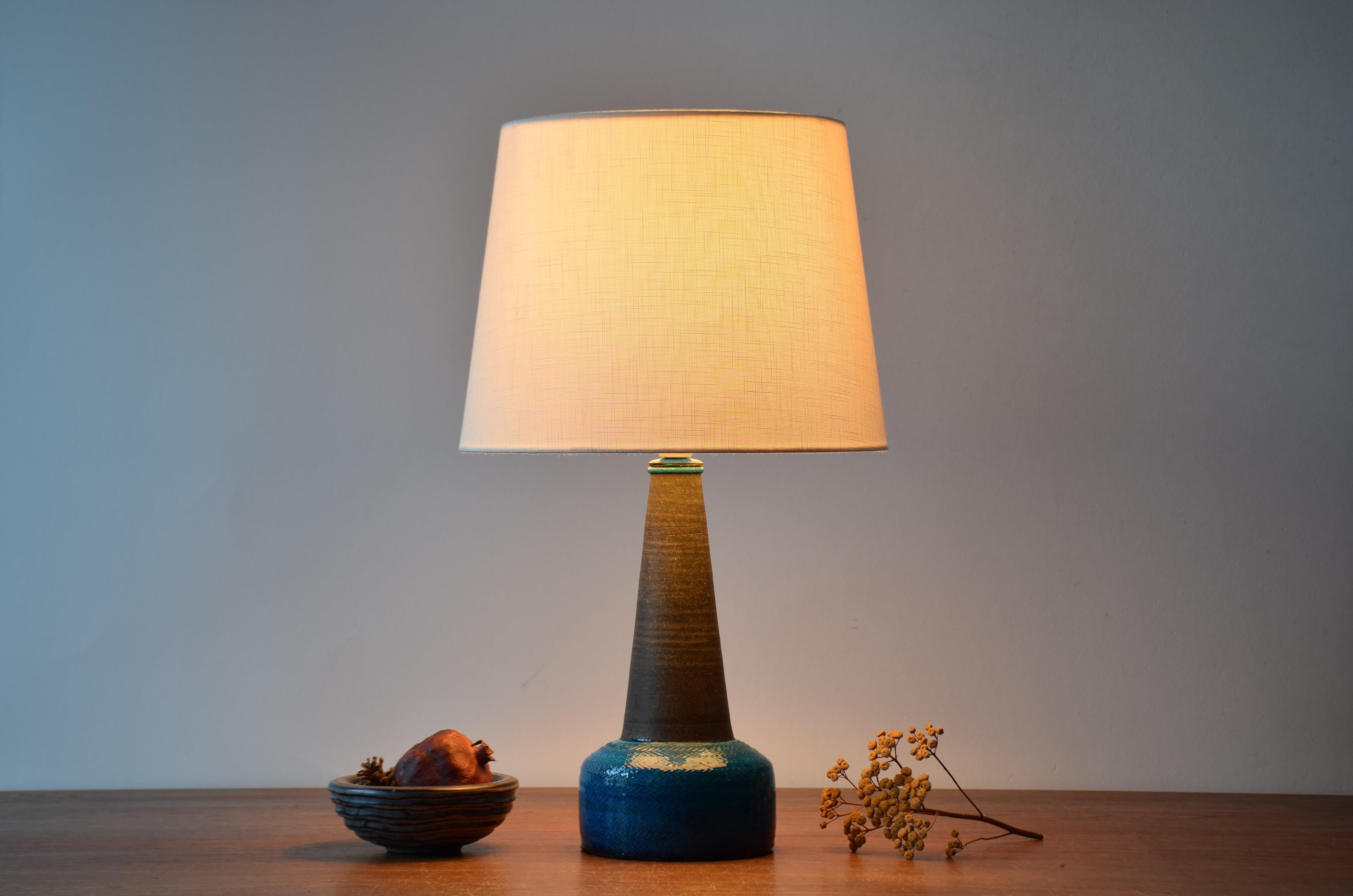 Midcentury ceramic table lamp from Danish Kähler (HAK).
The lamp was designed by Nils Kähler and made circa 1960s.
The neck is dark brown and has a smooth polished surface which is contrasted by the base covered with a glossy turquoise glaze showing