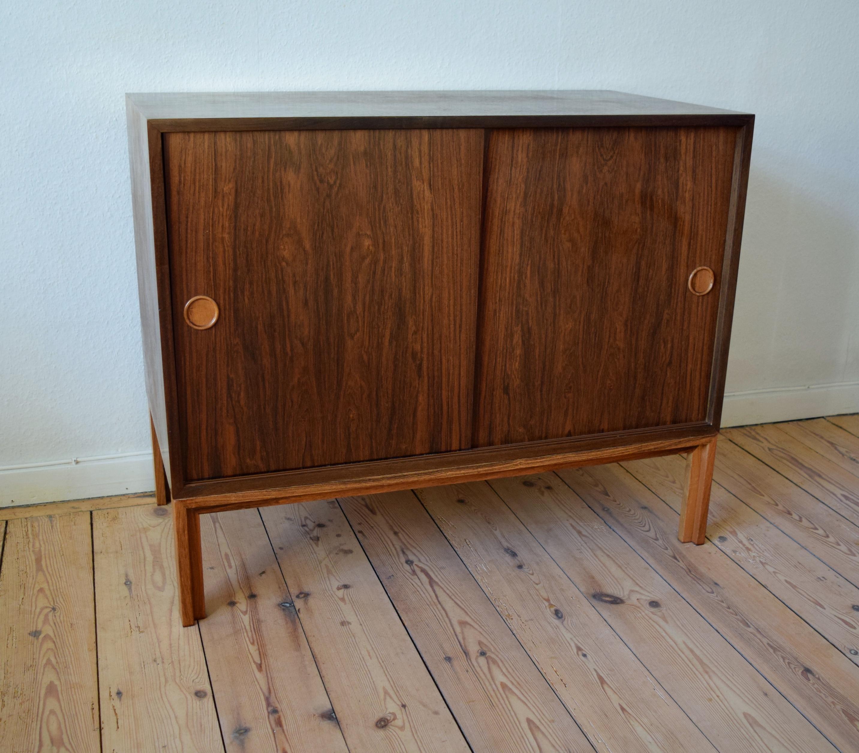 Danish rosewood bar cabinet by Kai Kristiansen for FM Møbler. Manufactured in the 1960s, this piece features two sliding doors with adjustable internal shelf and three felt-lined rosewood drawers. Sits on frame base solid rosewood legs. Striking