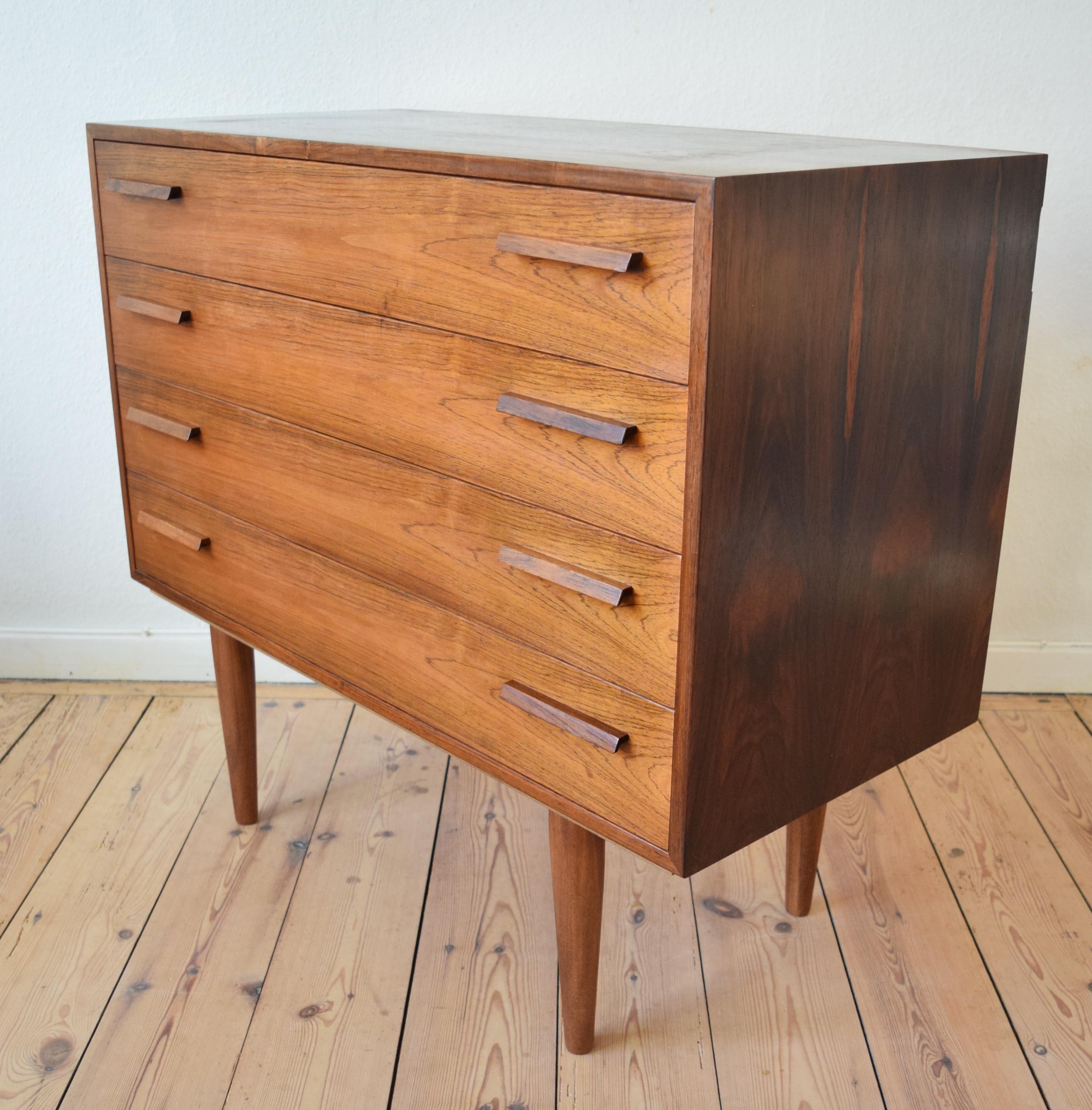 Danish rosewood chest of drawers by Kai Kristiansen for FM Møbler. Manufactured in the 1960s, this piece features four drawers with solid rosewood handles. Sits on turned and tapered legs. The unit is in a very good condition and apart from some age