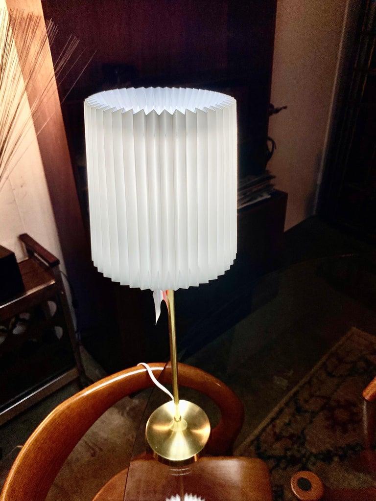 The classic Le Klint vintage lamp features the distinctive pleated shade in white with a brass base offers a timeless look. Le Klint's highly sought shades are still pleated by hand in Denmark. This mid-century lamp is in good condition.