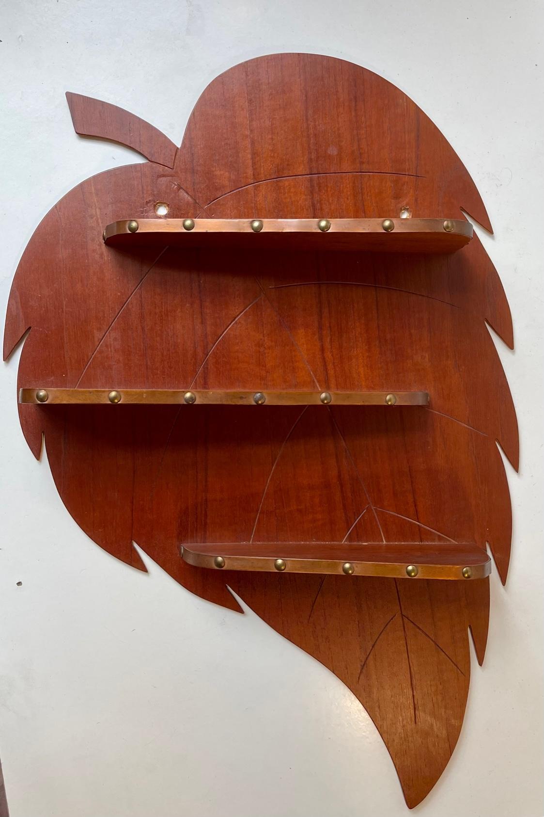 Skillfully crafted wall mounted spice-rack or display-shelf in shape of a giant leaf. The 3 asymmetrical shelves features decor in copper-band. Crafted by anonymous furniture maker in Denmark during the 1960s. Measurements: H: 60 cm, W: 40 cm, Dept: