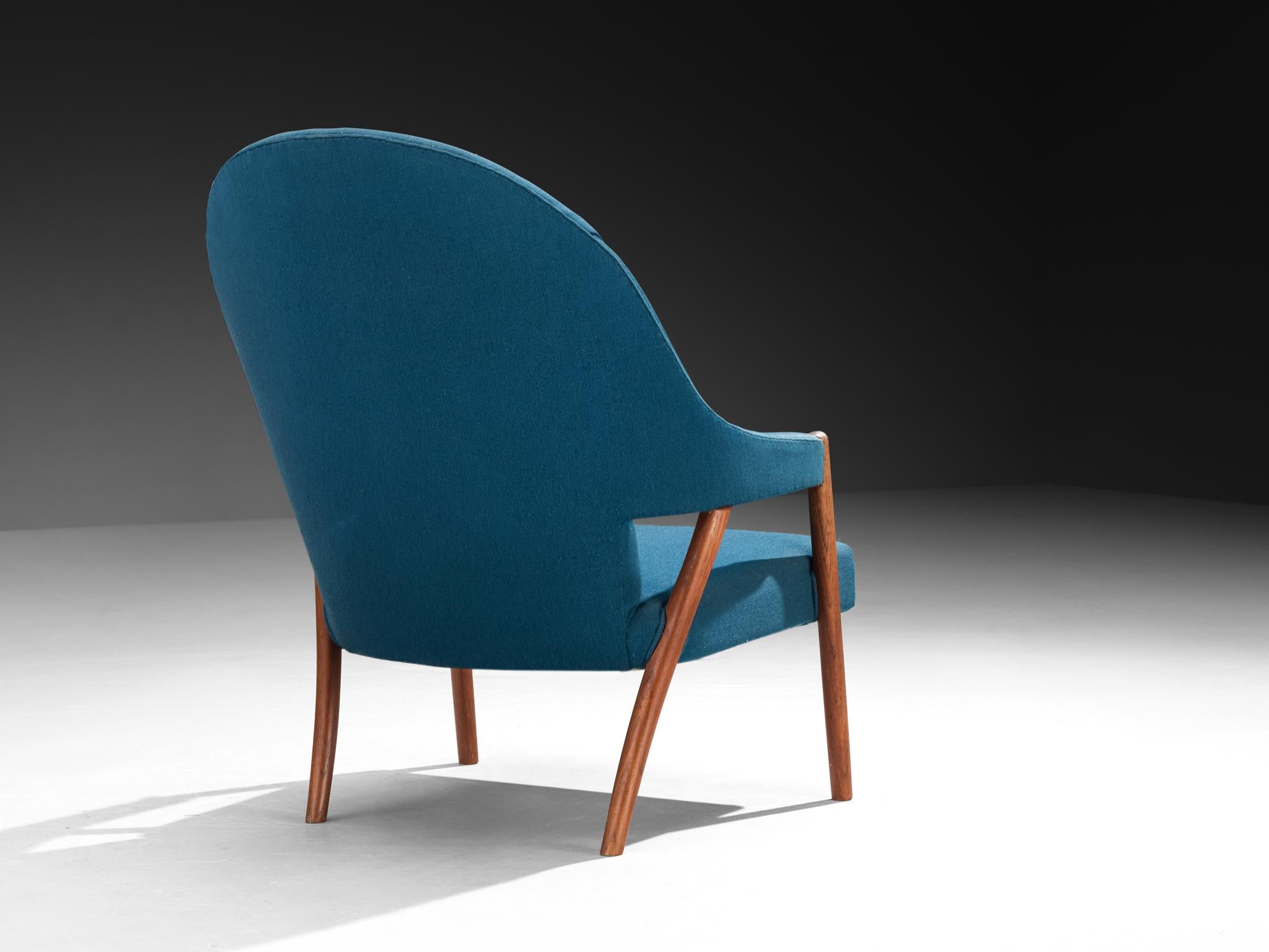 Sillón, tela, teca, Dinamarca, años 50. 

Esta silla es una tumbona danesa de los años 50. Su forma demuestra el compromiso escandinavo con la simplicidad refinada, la proporción orgánica y el uso honesto de los materiales. El respaldo es alto y