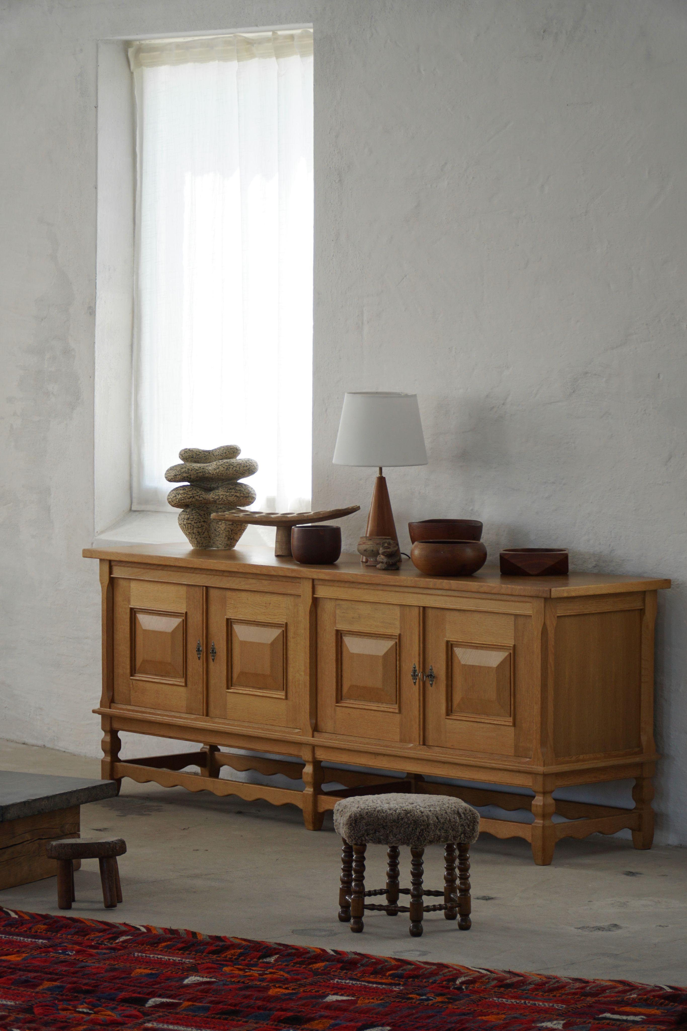 Appealing low modern sideboard, made in oak. Beautiful carved front design and rich storage space. Designed by Henning (Henry) Kjærnulf for Nyrup Møbelfabrik in the 1960s. Crafted from oak, the sideboard features a robust and imposing presence,