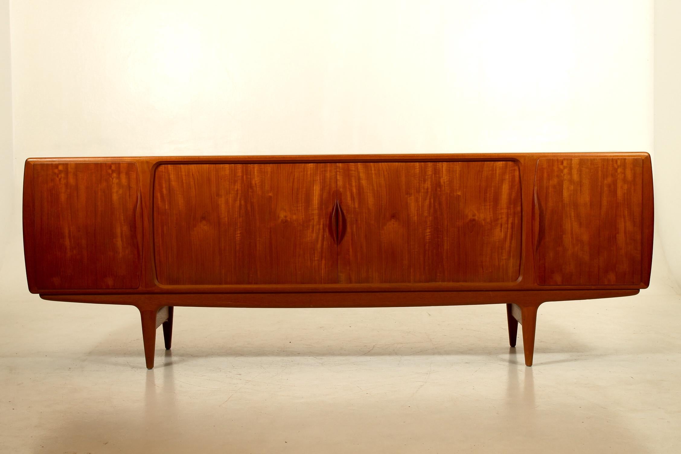 Long low teak sideboard with tambour doors and cabinets and drawers. Veenered back. Produced in the early 1960s by Uldum Møbelfabrik, Denmark. 
Model U15 designed by Johannes Andersen. Sold by H.C.Møbler, Copenhagen, Denmark.