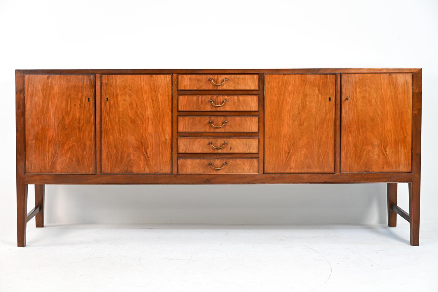 This gorgeous credenza or sideboard features beautifully a figured Cuban mahogany exterior and solid blonde wood interiors, with five dovetailed drawers and two cupboards with adjustable shelves. Gently rounded edges, half-round trim, and elegant