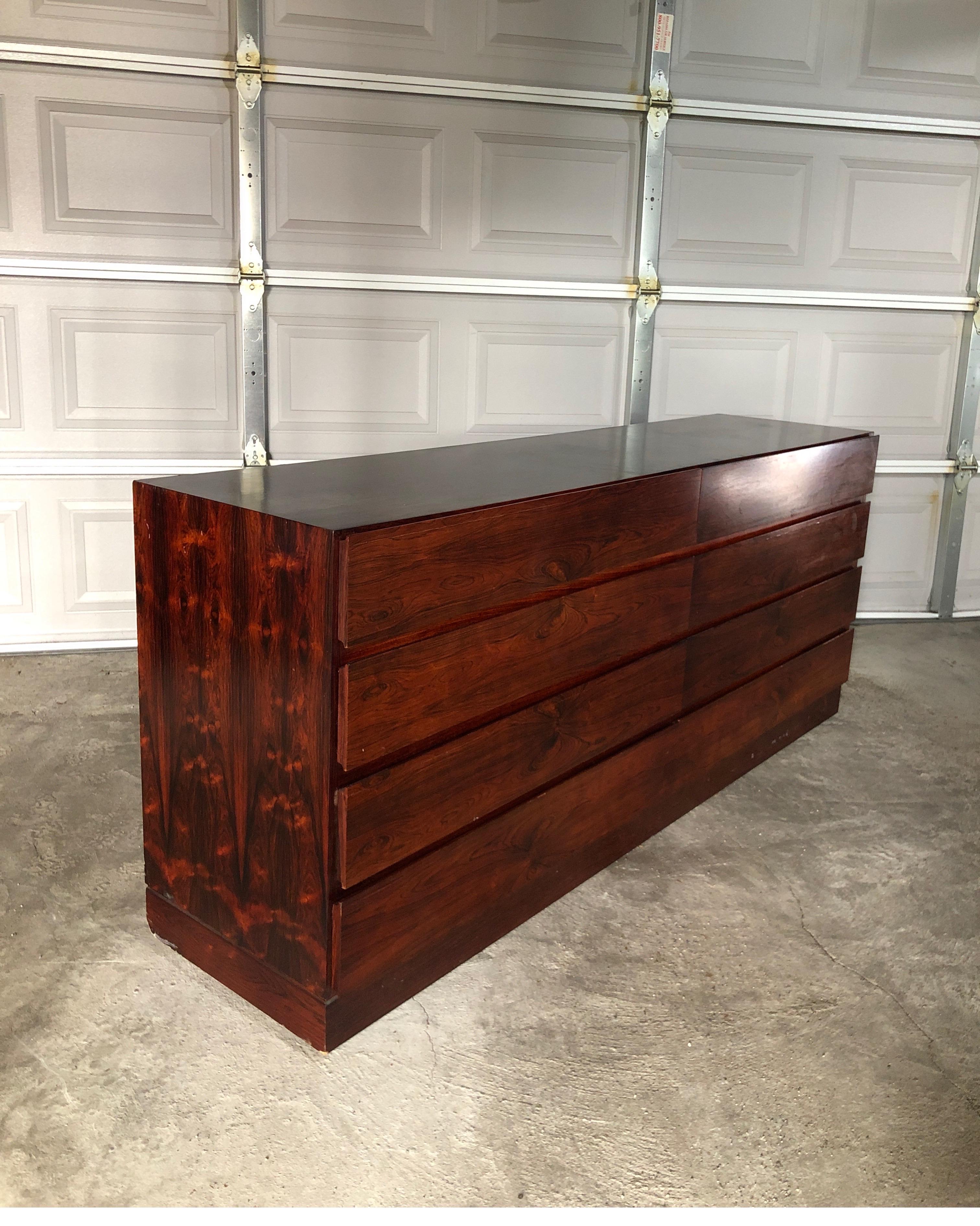 Elegant modern dresser designed and manufactured in Denmark in the 1960s.
Minimalist design with exotic and striking rosewood.
8 wide drawers with exquisite deep dark wood contrasting with light.
Dresser does show some signs of age and the top