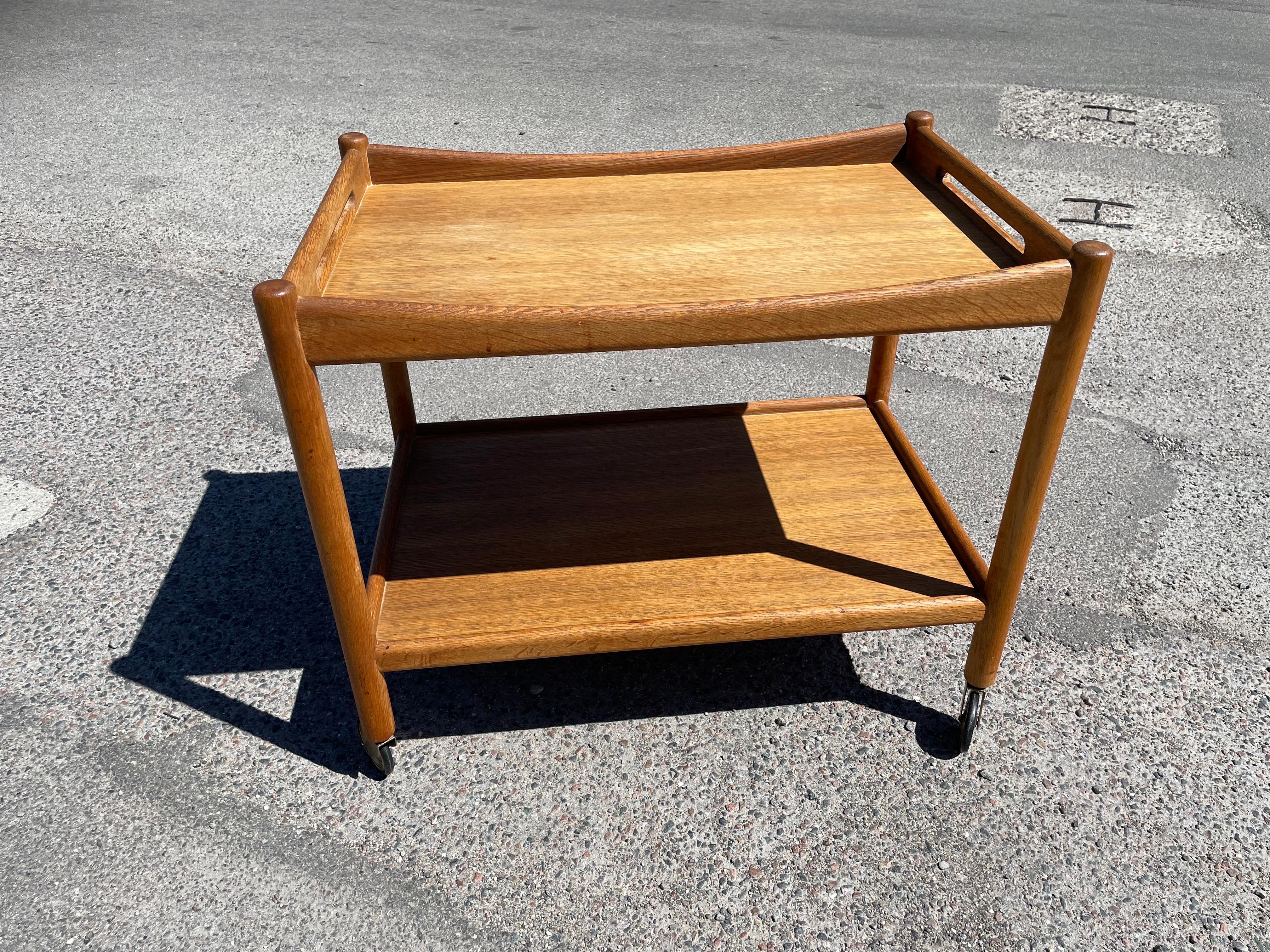 A stunning serving trolley designed by the legendary Hans Wegner for Andreas Tuck in 1959. Crafted from solid oak, this piece exudes both beauty and functionality. Despite its age, it remains in remarkable condition, with only minor traces of use as