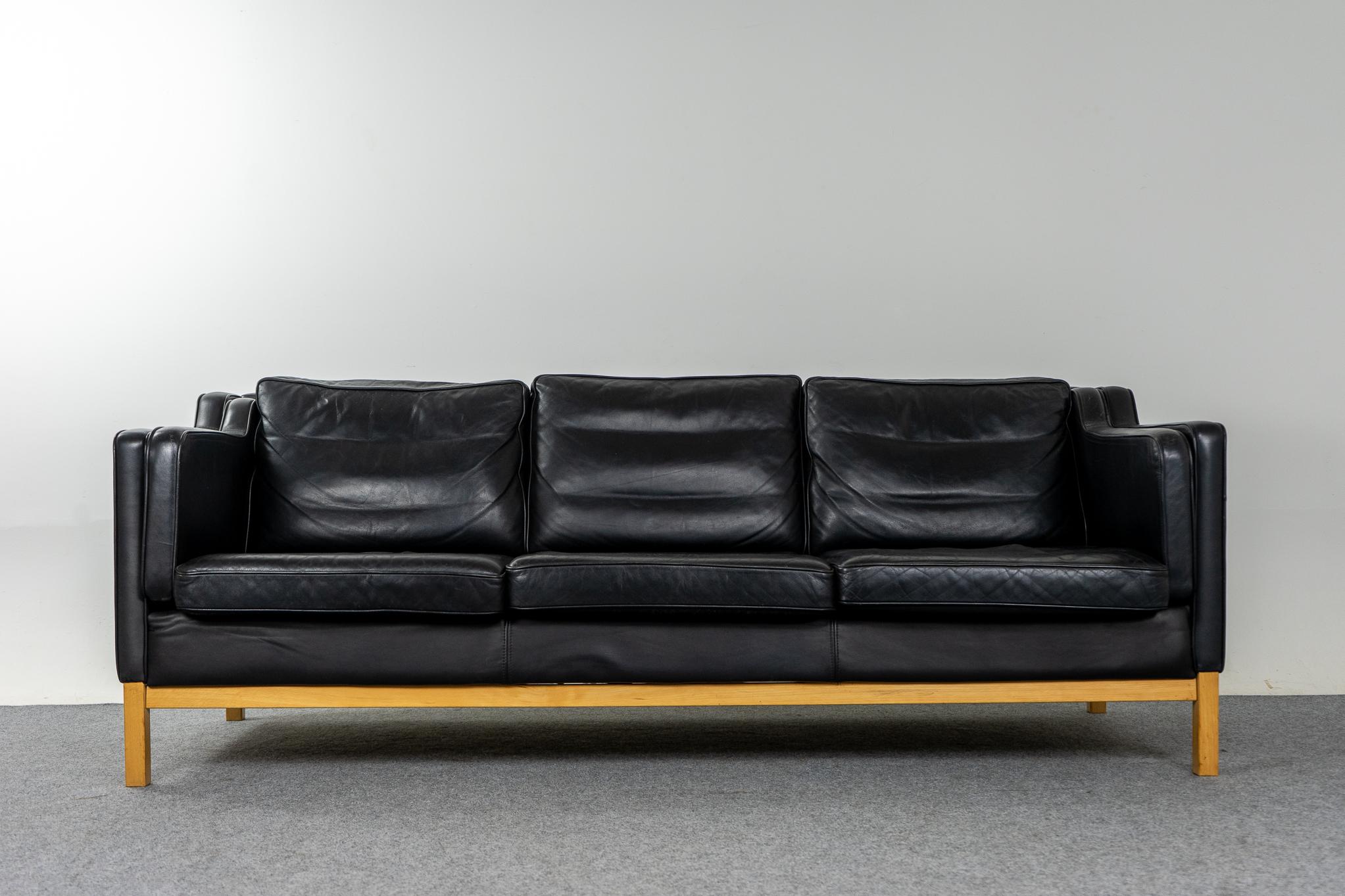 Danish Modern black leather three seat sofa, circa 1960's.Sofa rests on contrasting solid wood base. Original black leather is soft and supple while also being durable to ensure years of use and enjoyment. High quality construction and materials