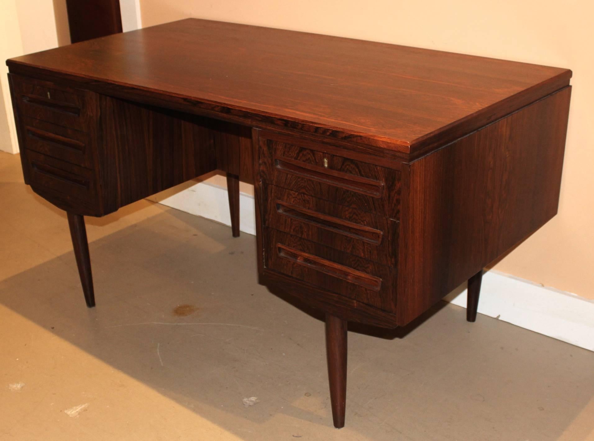 Danish Mid-Century Modern Brazilian rosewood desk with bar. The top of this desk features a beautiful slab of rosewood with active cathedral grain patterns. Two banks of three drawers sit on either side of the kneehole. A finished back with