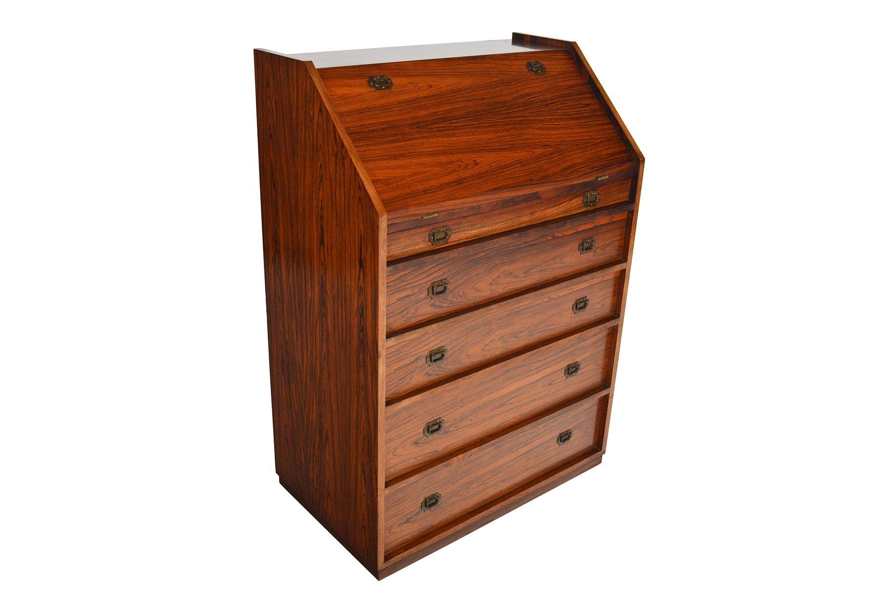 Compact and with concise details, this campaign secretary was designed by Henning Korch for CFC Silkeborg. Crafted in Brazilian rosewood, the large door drops to reveal a writing surface with four small drawers. Each drawer is adorned with brass