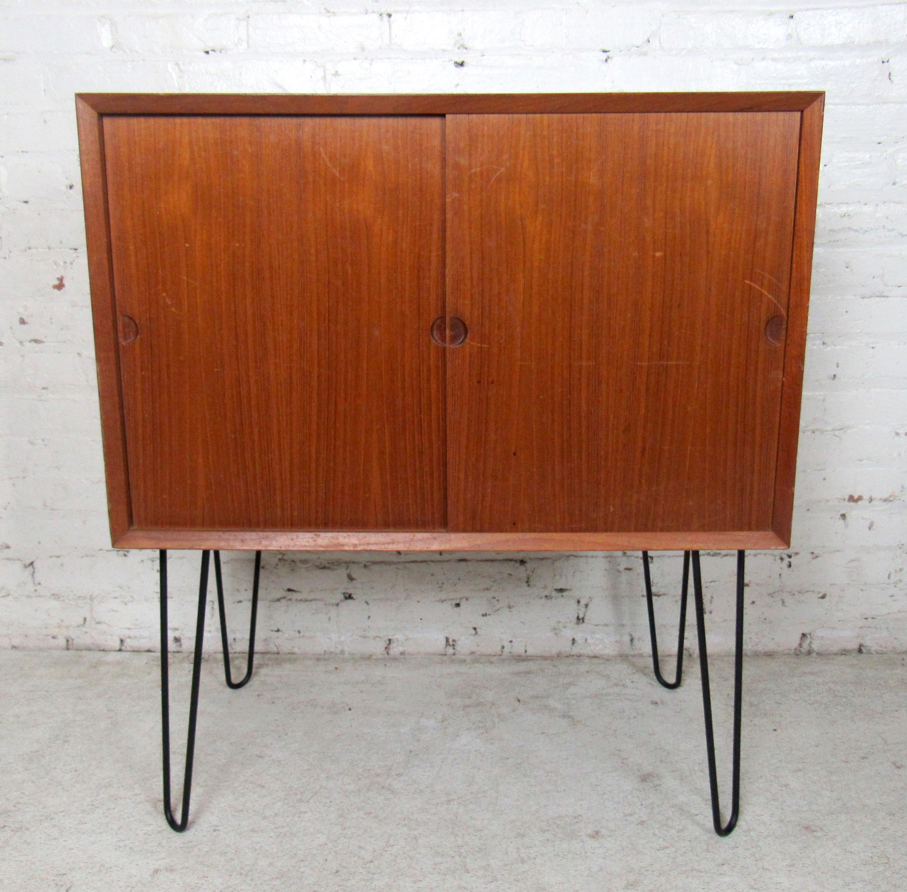 Vintage modern Danish teak cabinet featuring sliding doors, spacious storage space with one drawer on each side, on a set of hairpin legs.

-(Please confirm item location - NY or NJ - with dealer).