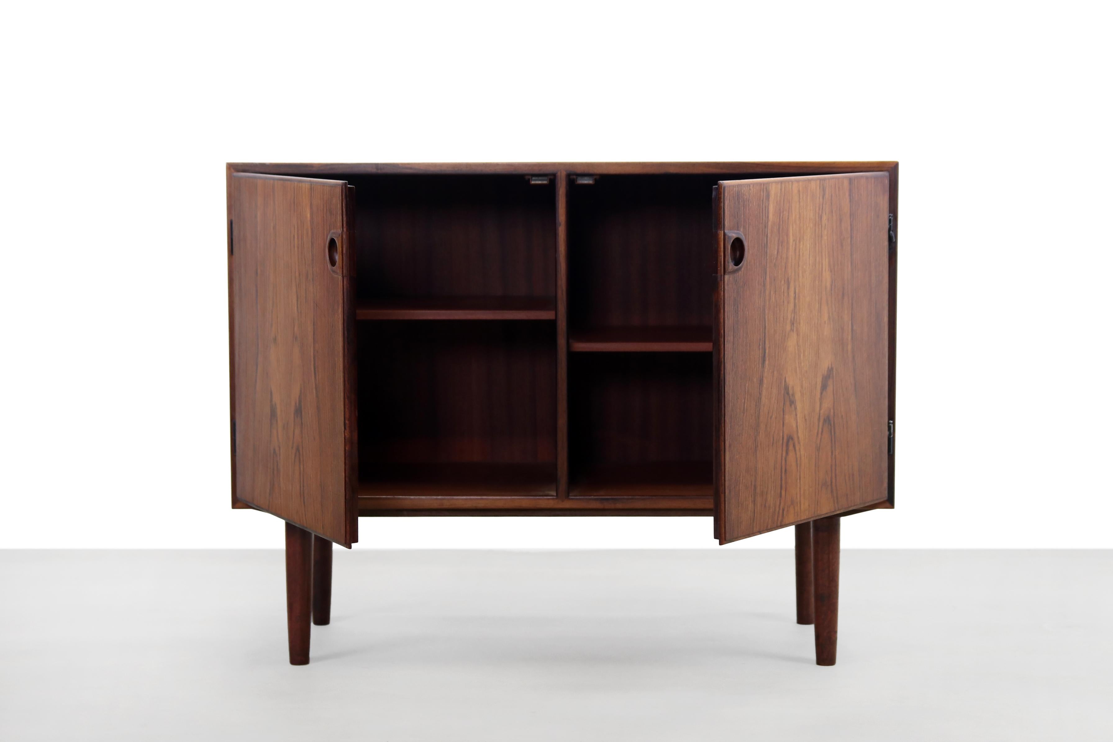 Beautiful Danish design sideboard with two doors. Made of veneer and very nicely shaped solid hardwood handles and legs. This dresser is not too wide and is therefore perfect for a somewhat smaller space. Due to the type of wood, this cabinet is