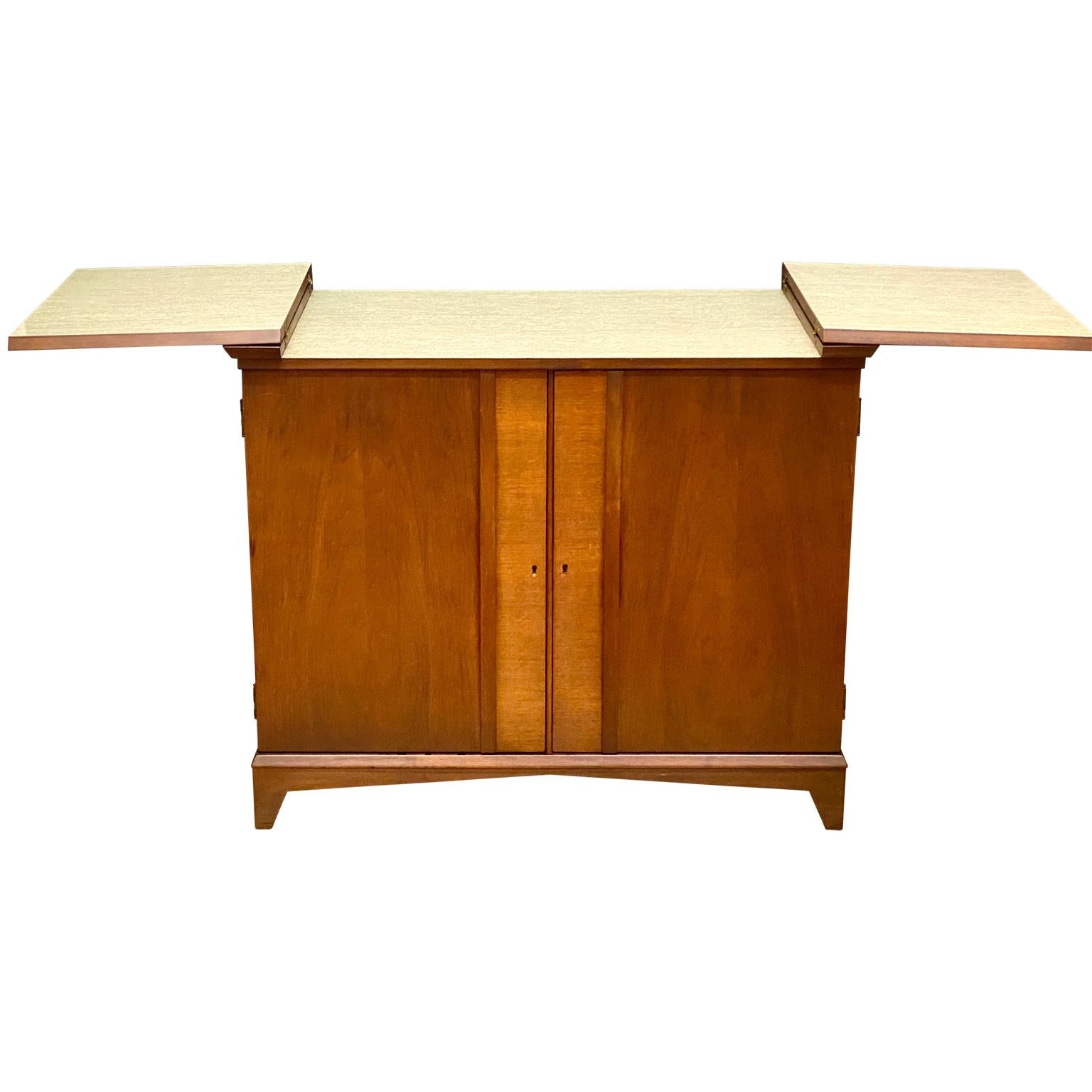 Danish Mid-Century Modern dry bar table with folding leaves.

This amazing dry bar has two fitted the doors for glasses and internal storage for wine and liquor bottles. The folding leaves are covered in the original linoleum upholstery.