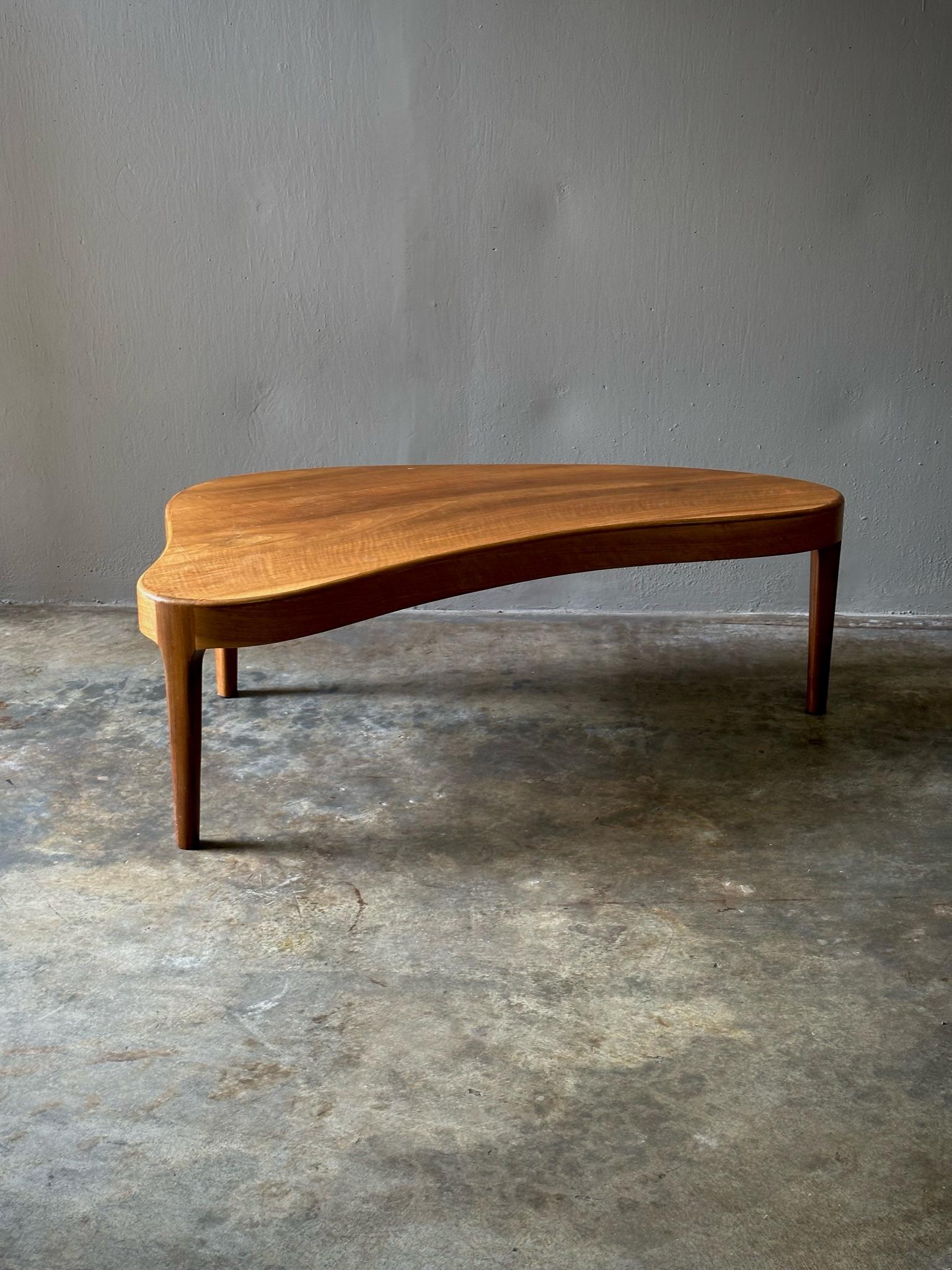 1950s Danish solid wood coffee table featuring slightly tapering three legged base and graphic, asymmetrical surface shape. Sleek and sexy yet with an organic, grounded sensibility.

Denmark, circa 1950

Dimensions: 50W x 26D x 17H