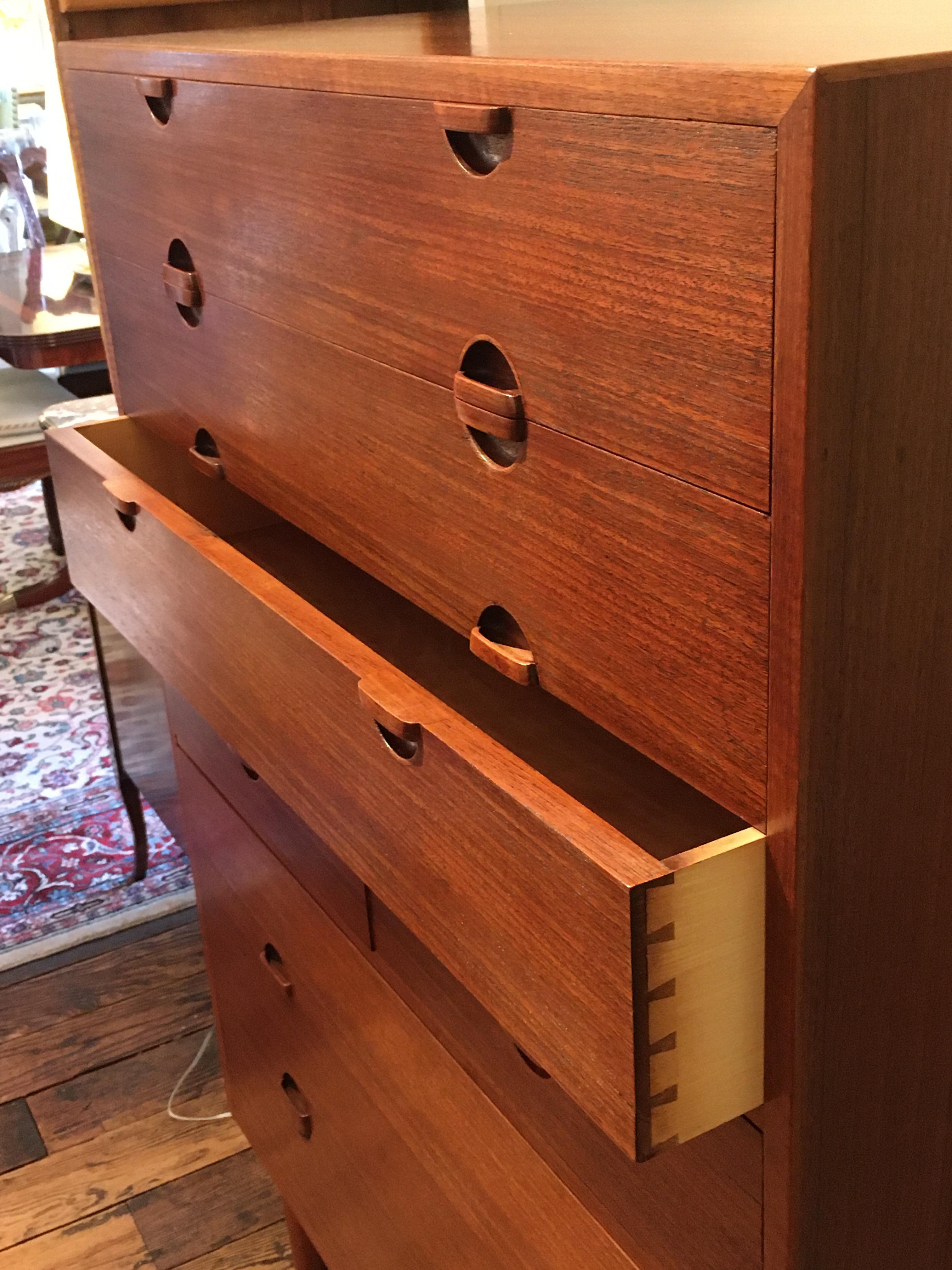 An iconic custom teak highboy chest of drawers made in Denmark, circa 1961, by Henrik Worts and Erik Worts, purchased at Den Permanente in Copenhagen. The 10 drawers have beautifully crafted inset wooden handles and dovetailing. Just