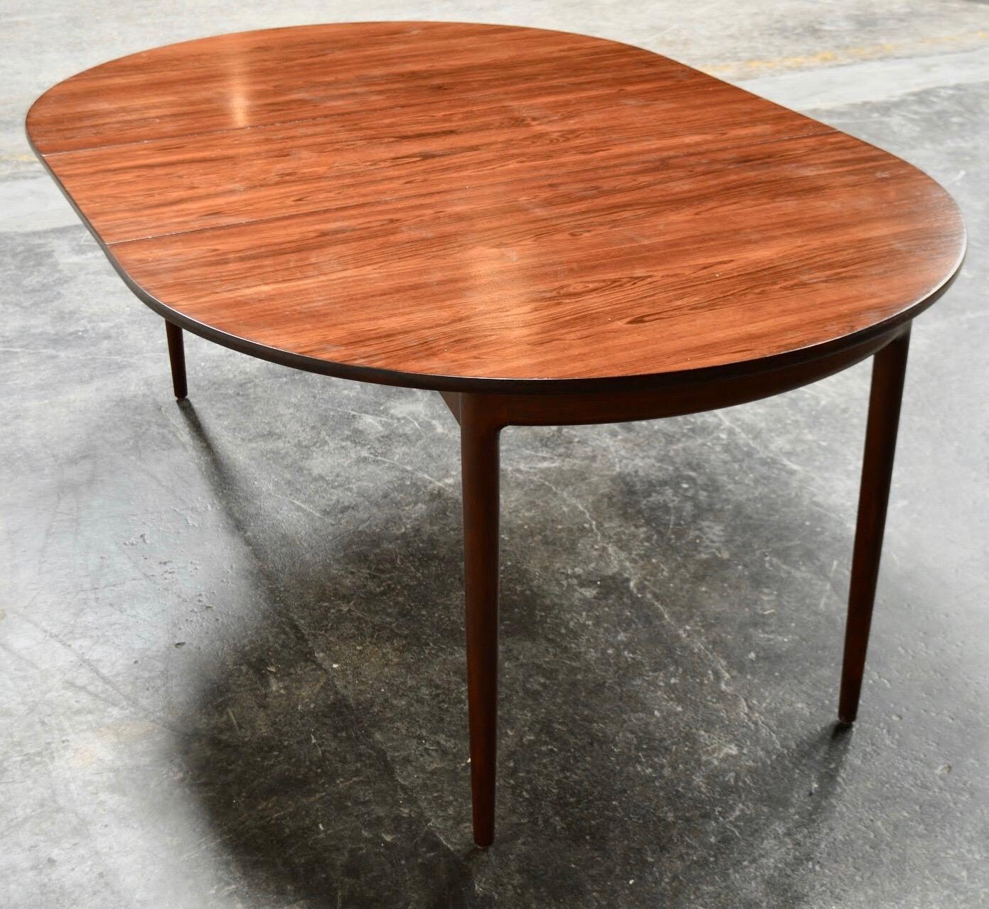 Sturdy midcentury oval or oblong dining table with one extension leaf. Made of both solid and veneer jacaranda wood, often mistaken for, and a close cousin of rosewood and palisander.

Due to the richness and depth of the Jacaranda wood grain,