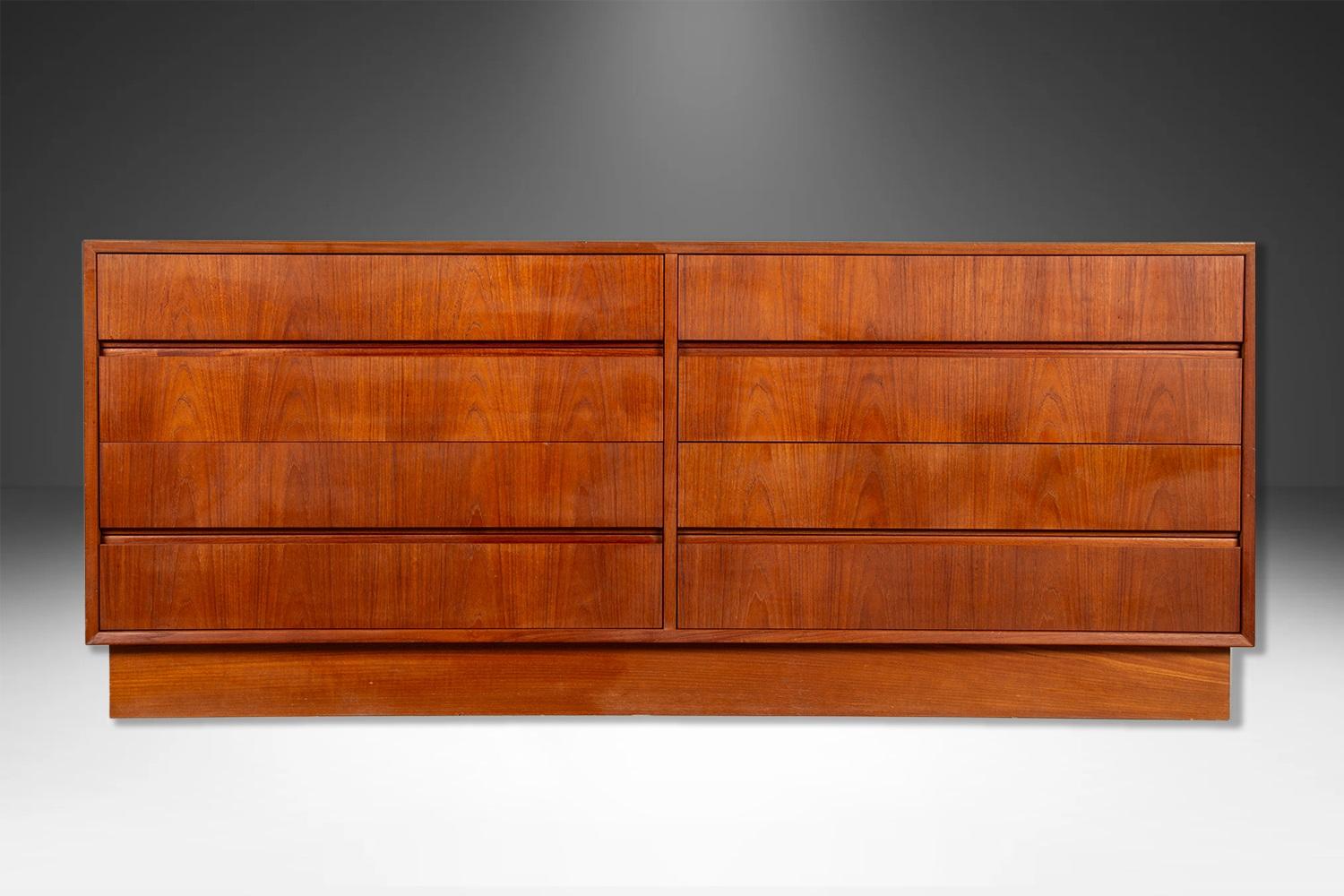 Attractive long low Danish modern sleek smooth face teak 8 long low dresser. This is a very simple yet modern 8 drawer design. Each drawer has beautiful medium tone stunning teak grains with attractive inset slit drawers carved out minimal pulls. At