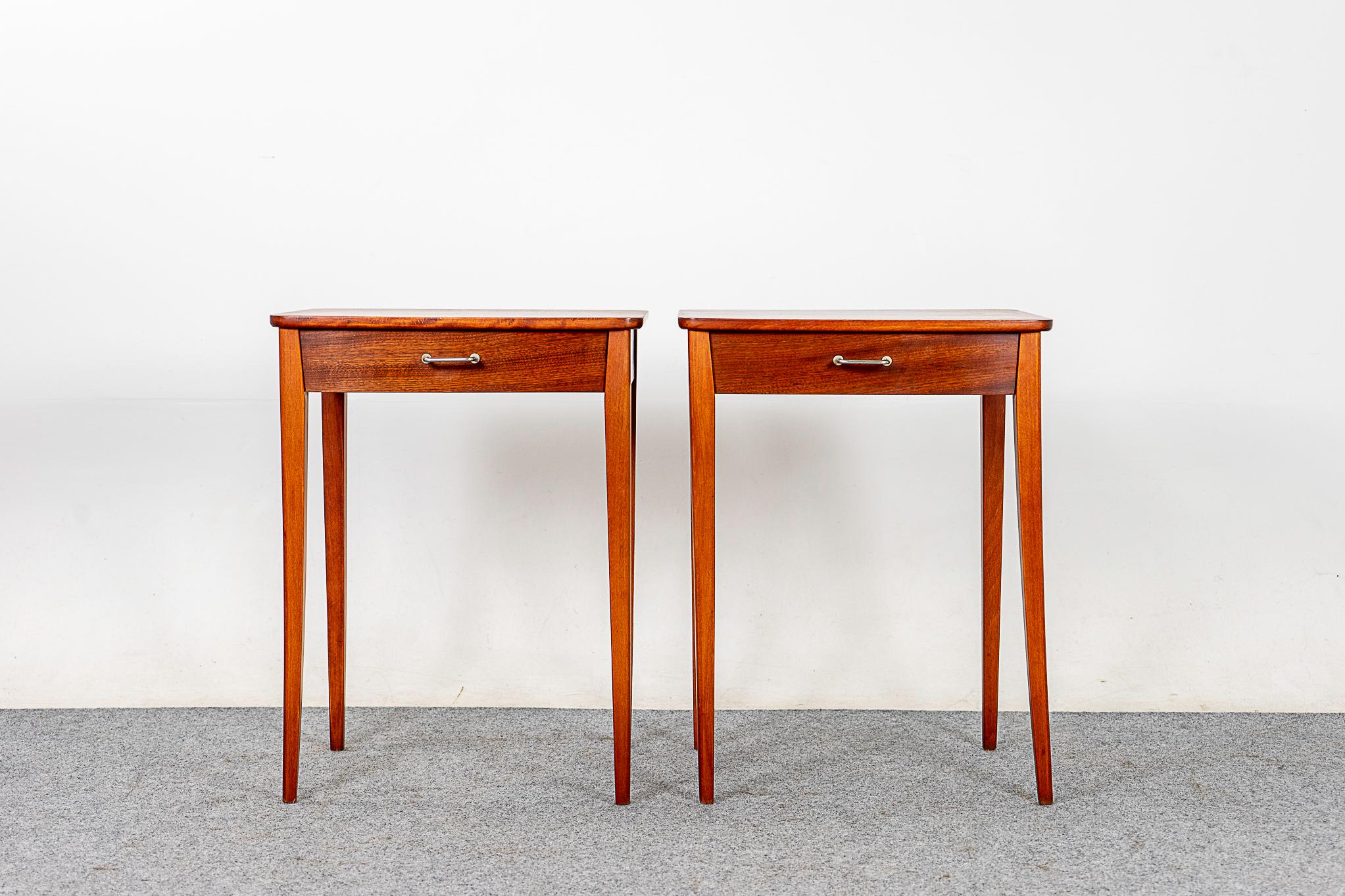 Set of 2 Mahogany bedside tables, circa 1960's. This pair of nightstands features beautifully veneered case, slender tapered legs and slim drawers with metal pulls.