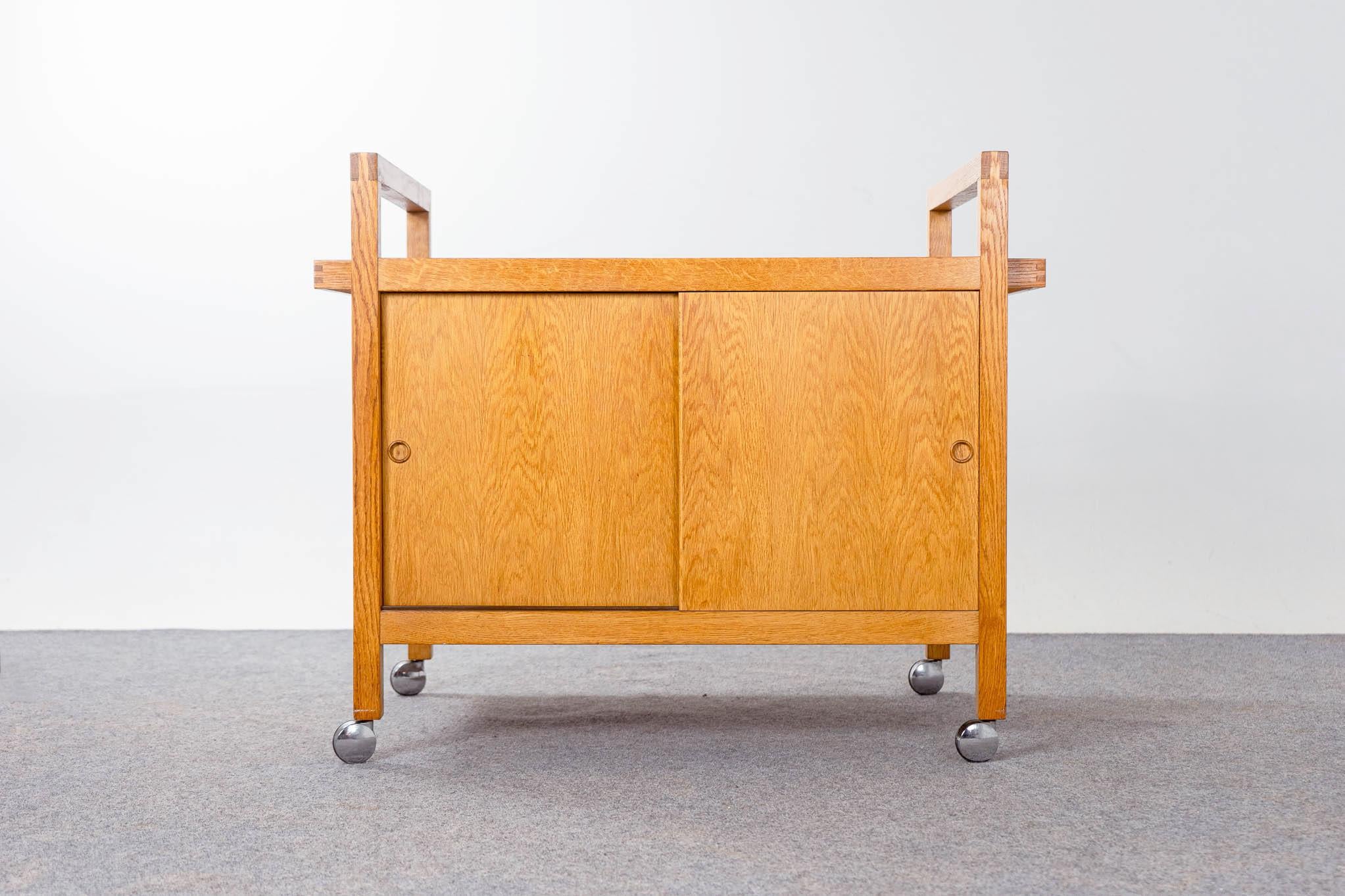 Oak Danish Modern bar cart, circa 1960's. Unique cart with sliding doors on both sides, providing ample storage for all the different heights and shapes of your bottles. Melamine mixing top slides open to access the contents below! Lovely box joint