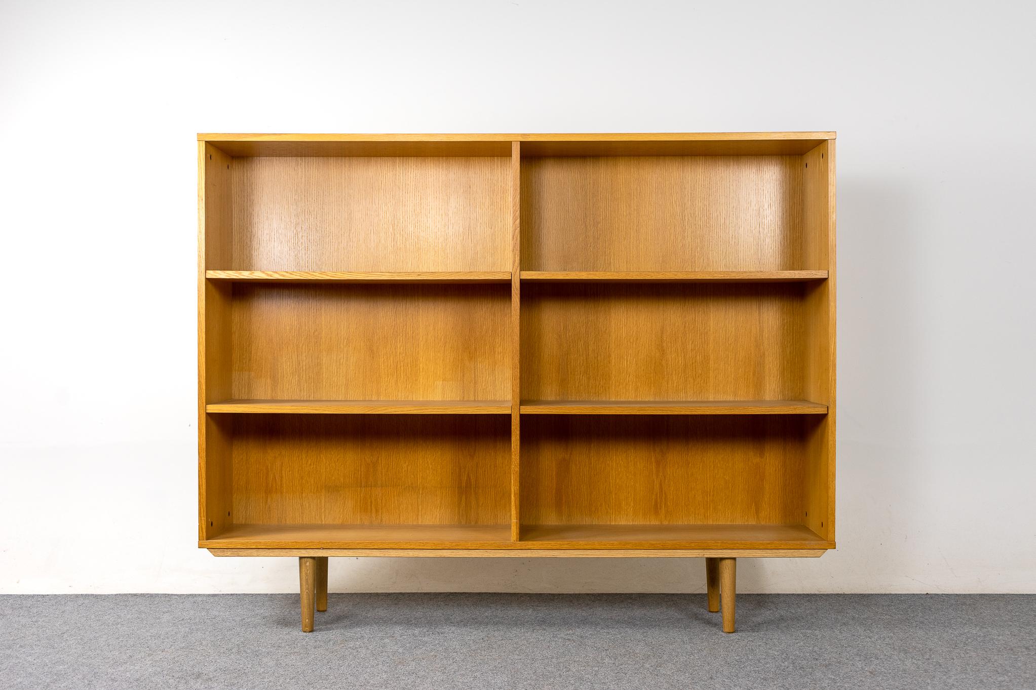Oak Danish Modern bookcase, circa 1960's. Clean modern bookcase with adjustable shelving, 16 hanging options. Case sits upon removable, tapered solid wood legs. Finished back too! Very nice vintage condition.

Unrestored item, some minor marks