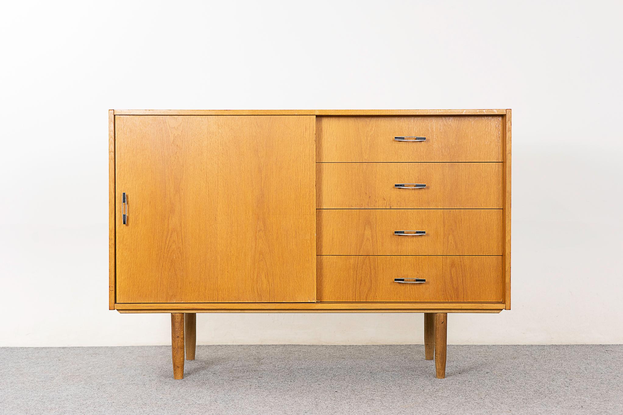 Oak Danish cabinet, circa 1960's. Book-matched veneer top and drawer faces, a handy combination of drawers and a removable interior shelf. Sleek metal handles and tapered legs.

Please inquire for remote and international shipping rates.