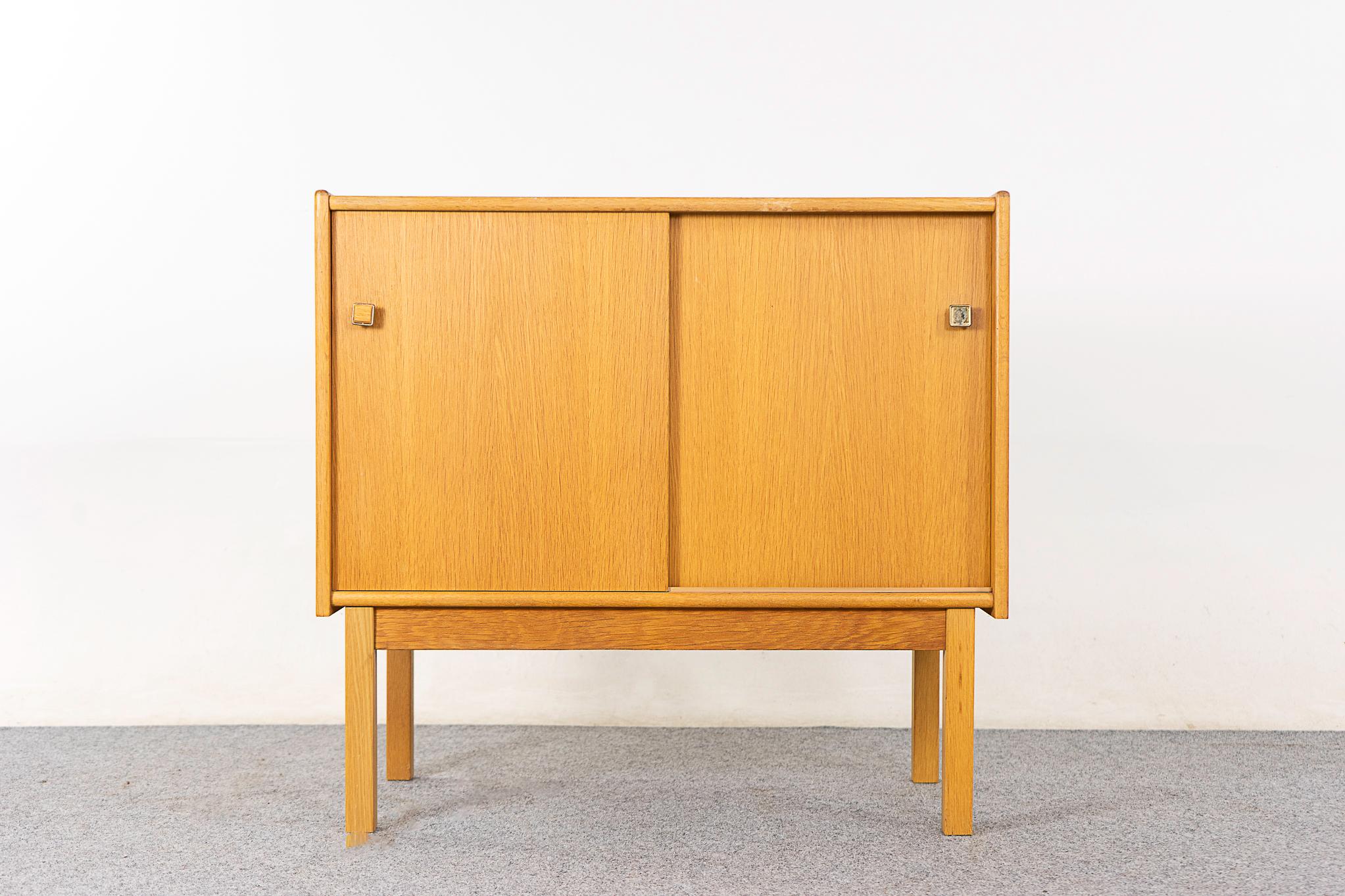 Oak mid-century cabinet, circa 1960's. Clean, simple lined design with book-matched veneer. Sliding doors open to fixed height shelf.

Unrestored item with option to purchase in restored condition for an additional $150. Restoration includes: