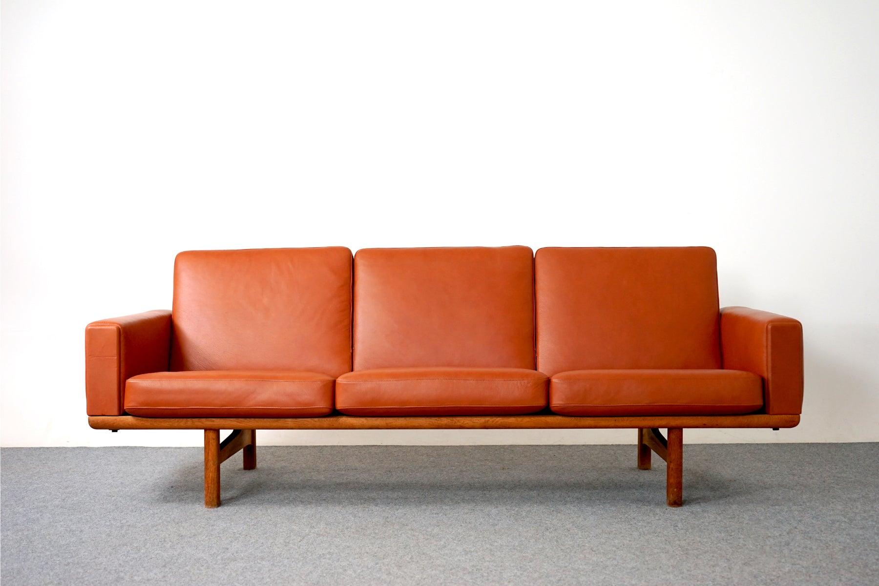 Dänisches Sofa aus Eiche und Leder, Modell GE 236/3 von Hans Wegner für Getama, ca. 1960. Das Gestell des Dreisitzer-Sofas ist aus massiver Eiche gefertigt. Die abnehmbaren, neu gestalteten cognacfarbenen Lederkissen sind mit originalen Metallfedern
