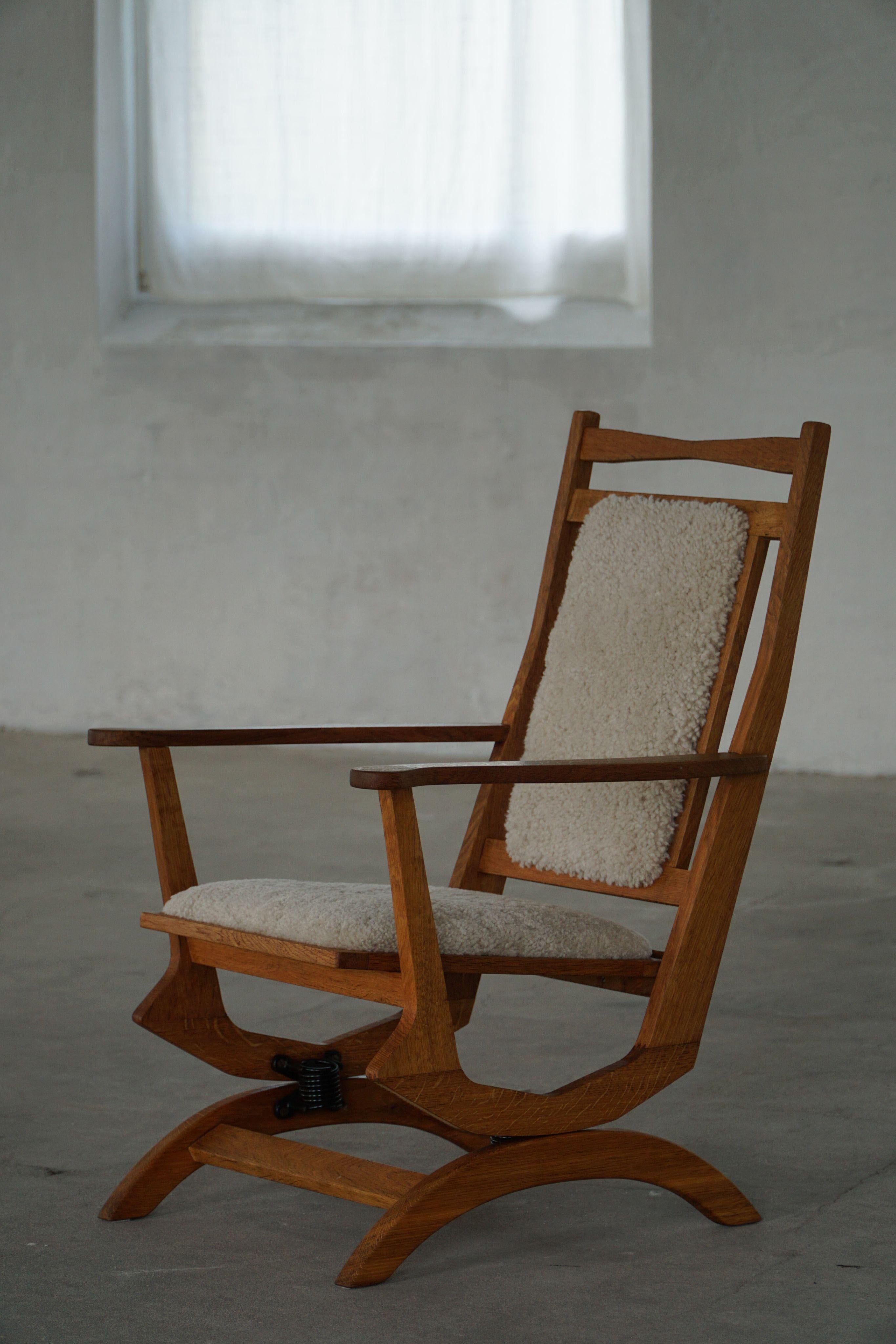 Questa elegante sedia a dondolo danese con schienale alto degli anni '50 è un raffinato esempio di artigianato di metà secolo. Realizzata in rovere massiccio, la struttura presenta guide delicatamente curve e braccioli scolpiti che mettono in