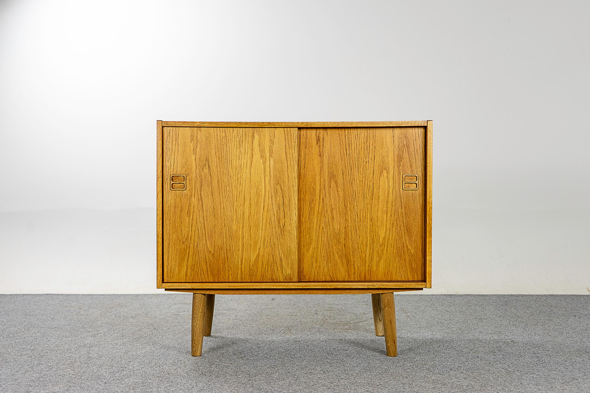 Oak Danish slider cabinet, circa 1960's. Clean, simple lined design highlights the exceptional book-matched veneer. Sliding doors open to reveal interior shelf.

The perfect piece for everyday use.

Please inquire for international shipping rates.