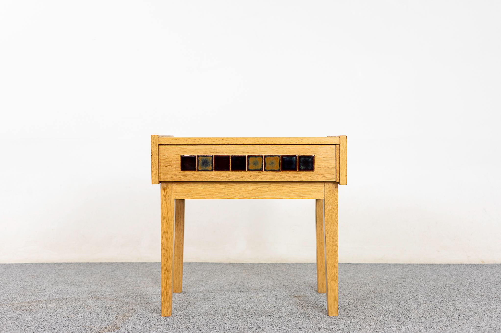 Oak & tile mid-century bedside table, circa 1960's. Veneered case with solid legs. Sleek dovetailed drawer with ceramic tiles for a pop of color. 

Please inquire for remote and international shipping rates.