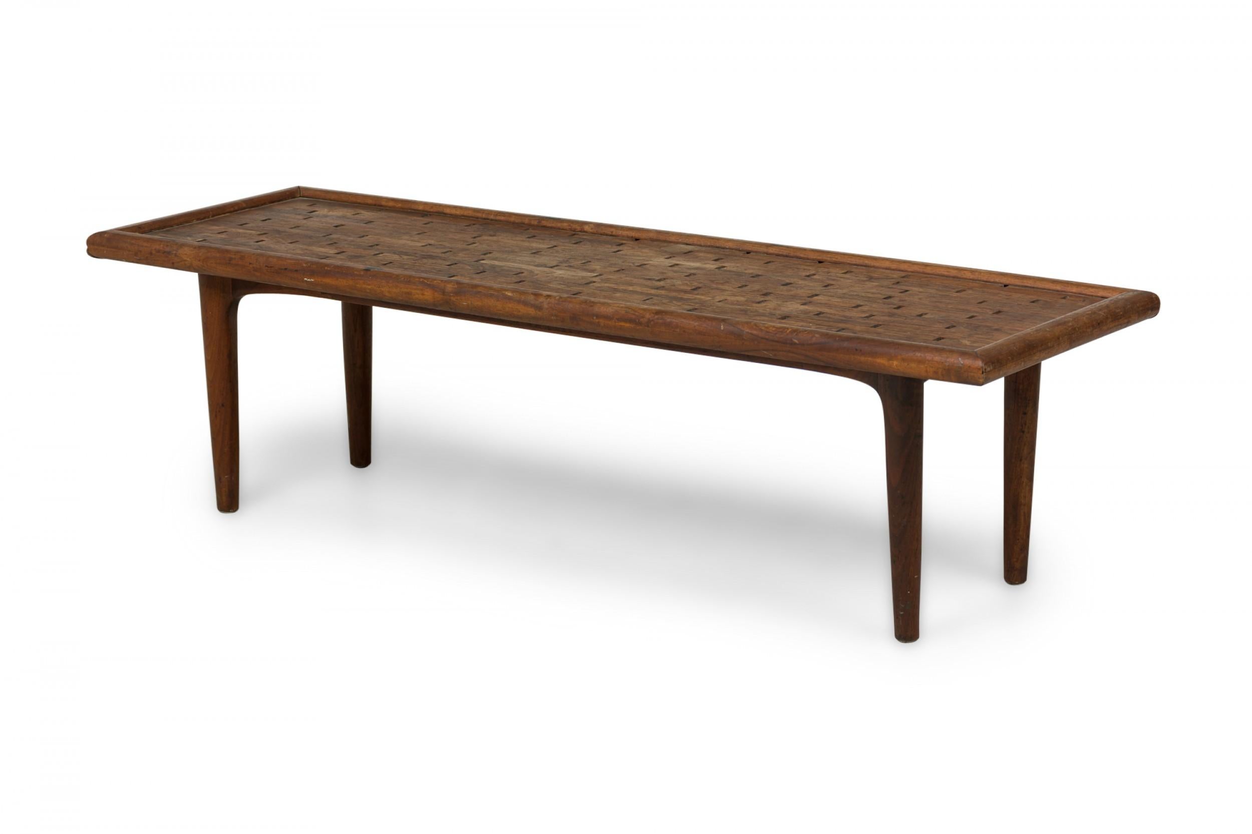 Table basse rectangulaire danoise moderne du milieu du siècle, construite en bois de rose, avec un plateau incisé géométriquement et une moulure de bordure basse, reposant sur quatre pieds cylindriques effilés.

Usure mineure de la finition.