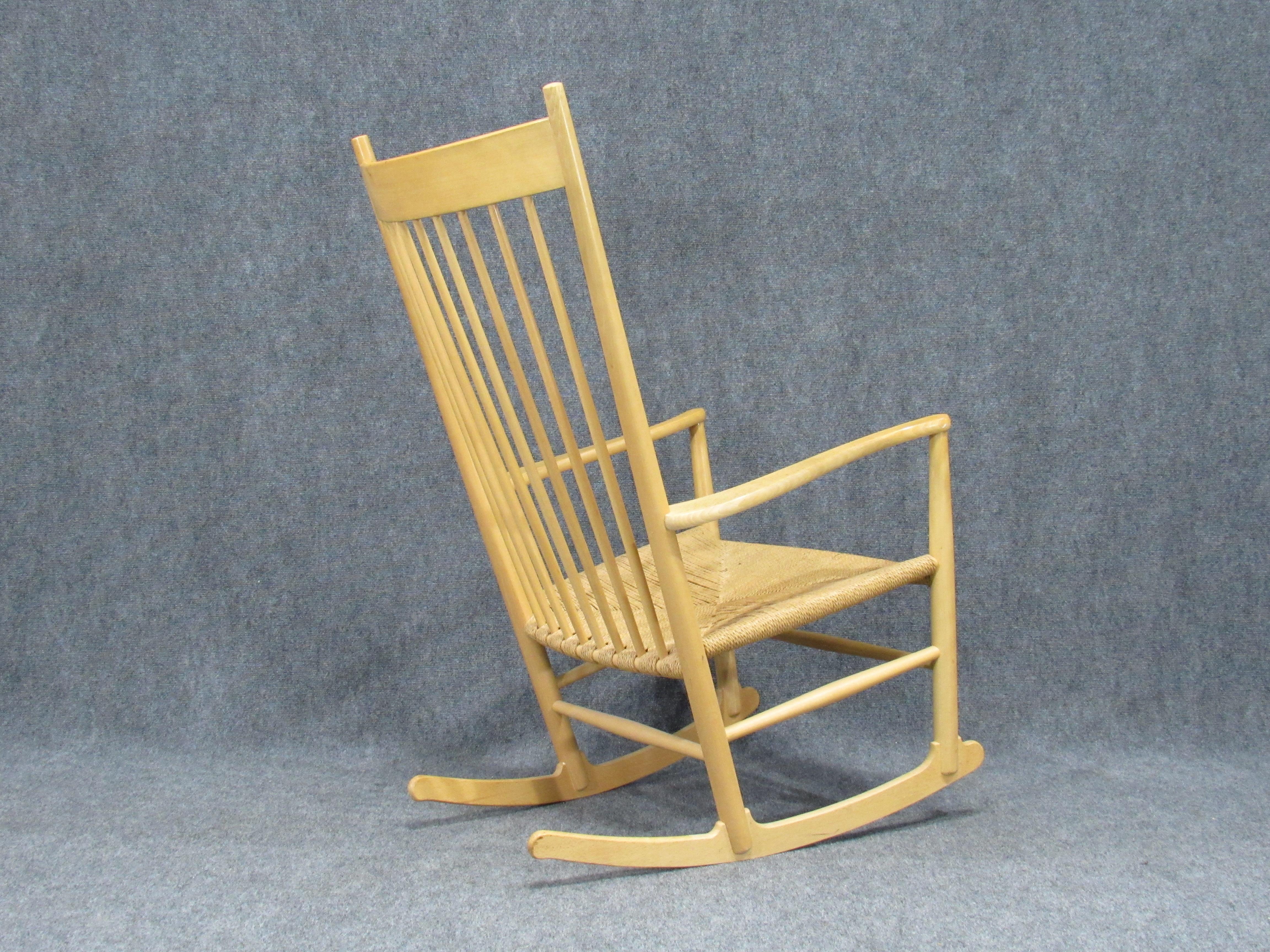 This spindle-backed model J16 rocking chair J16 was designed by Hans Wegner in 1944 and manufactured by Mobler F.D.B. Denmark. The beech frame and 3-ply hemp cord seat seating is in a very excellent vintage condition. The Scandinavian Modern