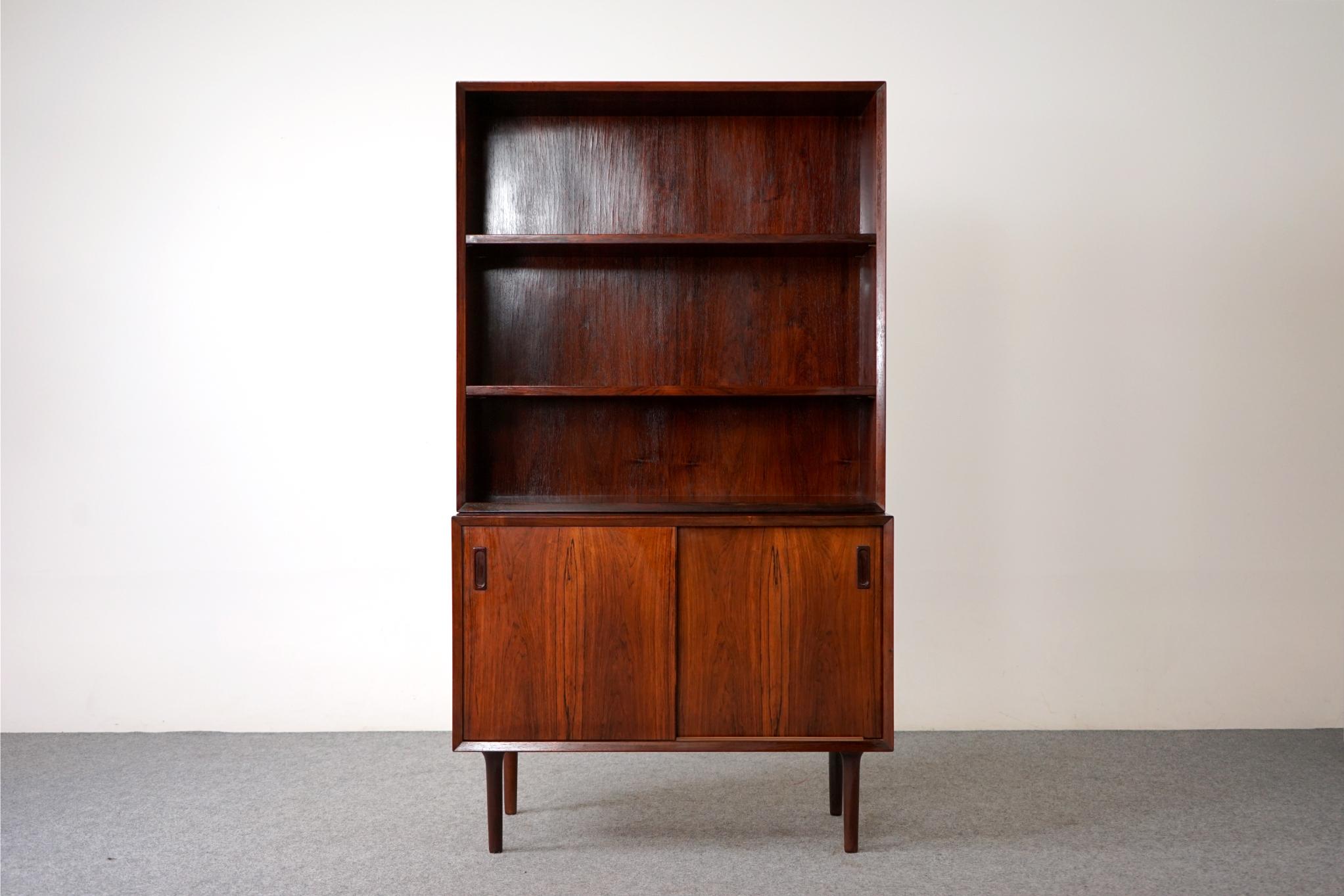 Rosewood Scandinavian bookcase/cabinet by Lyby Mobler, circa 1960's. Open bookcase rests upon a sliding door cabinet, could be used separately. Case sits upon removable, tapered solid wood legs, adjustable shelving to suit your needs! Stamped