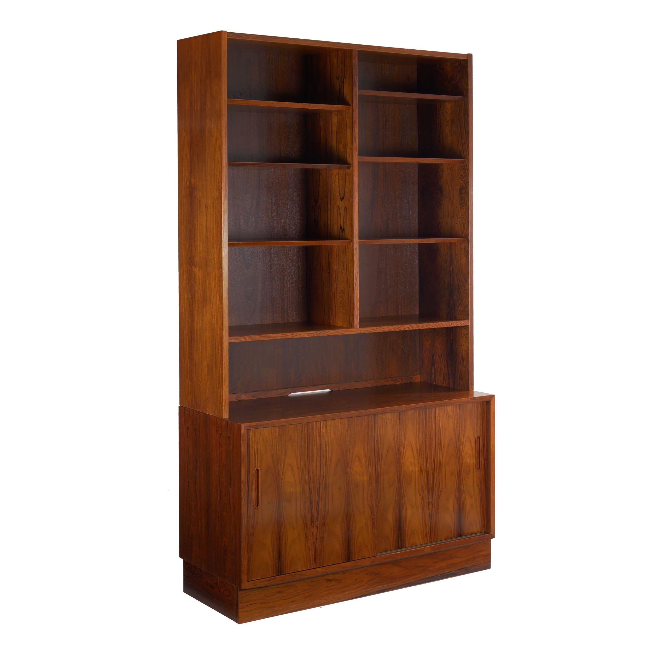 This most striking bookcase-over-cabinet by the firm of Hundevad & Co. is austere in form while rich in surface. Hundevad & Co was founded in 1935 in Ulfborg, Denmark and had quite a significant output during the period. The present piece is