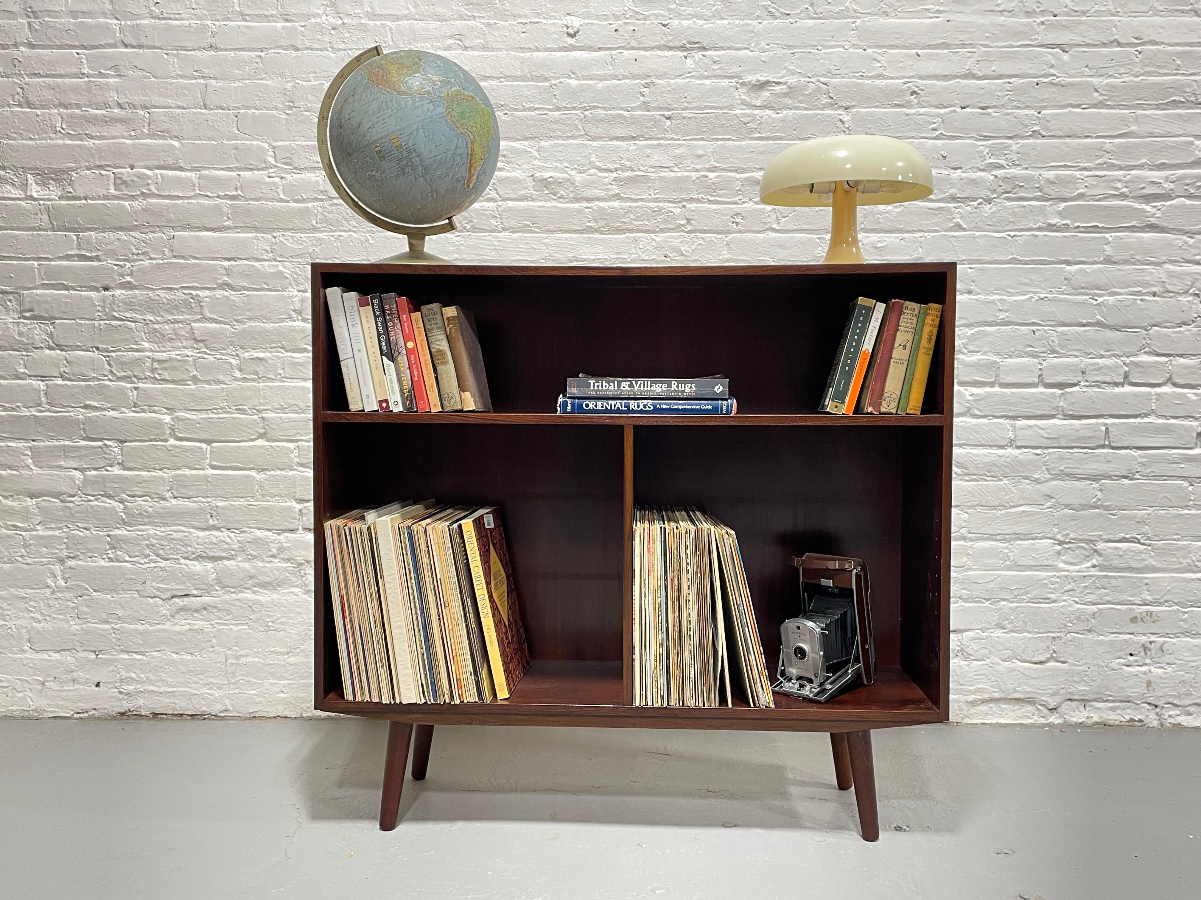Danish Mid Century Modern Rosewood Bookcase / Vinyl Storage, c. 1960’s.  Loads of storage for all your books and collectables or vinyl collection across the two lower areas once the lower shelves are removed.   Constructed in rosewood and its deep,